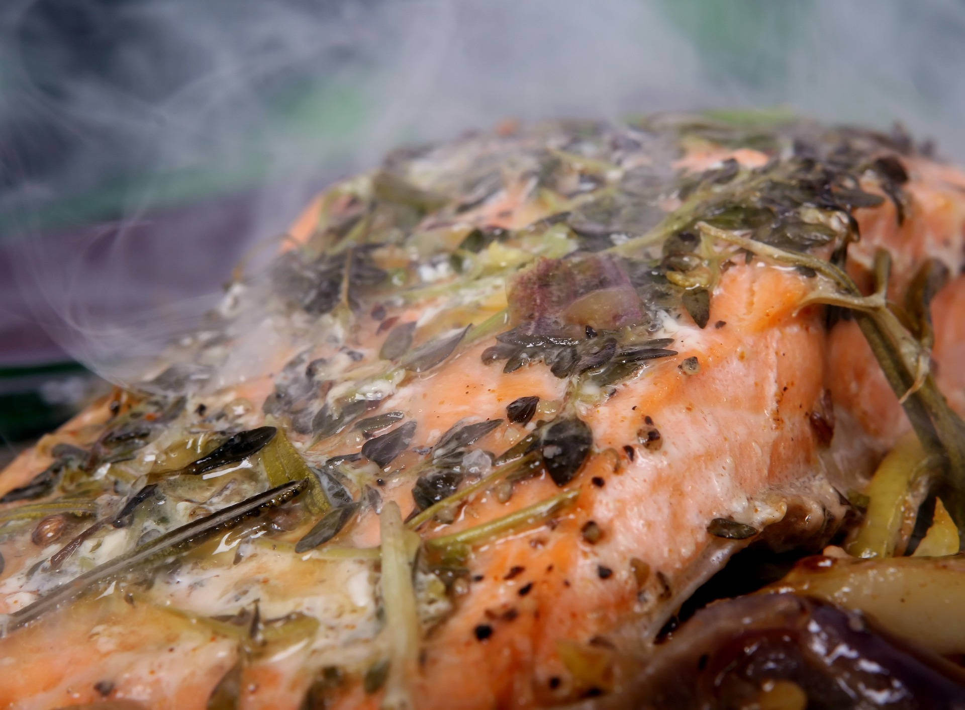 煙燻海 bass 魚排 壁紙 — 特寫鏡頭：一塊蒸三文魚柳，上面鋪滿香草和香料，散發出芳香煙霧。