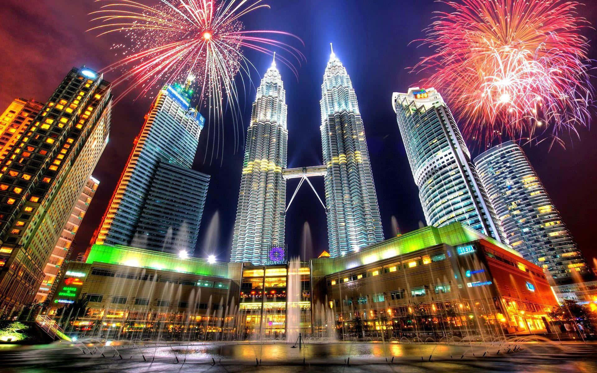 Malaysia 桌布 壁紙 — 煙花在雙峰塔上空綻放，下方燈光噴泉噴射，構成璀璨的城市夜景。