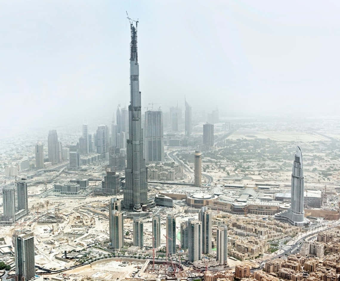 Burj Khalifa 桌布 壁紙 — 煙霞籠罩下，杜拜現代天際線上正在興建的哈利法塔的鳥瞰圖。