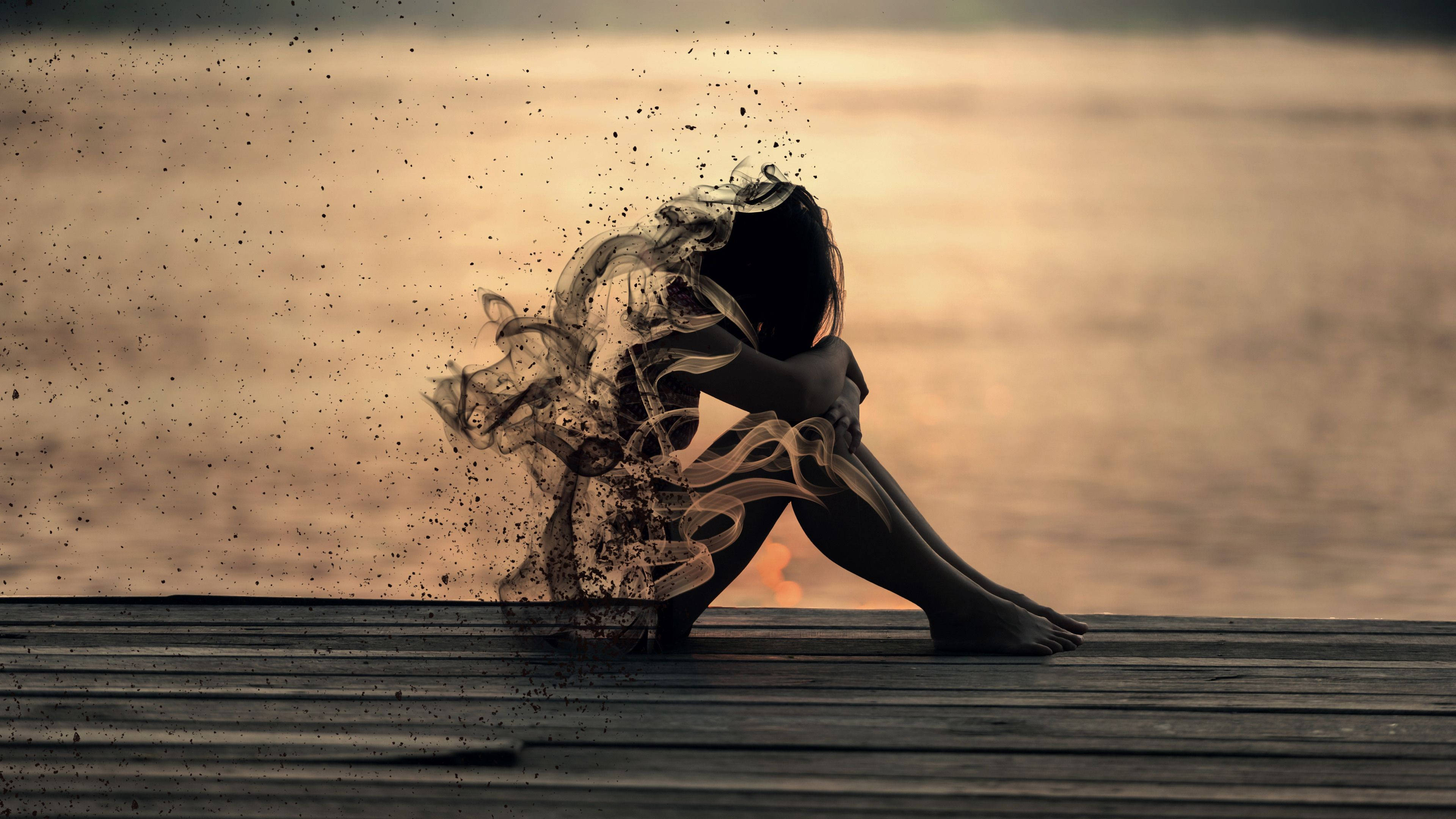 煙霧中哭泣的女孩美學 壁紙 — 一個人獨自坐在木碼頭上，其形態在溫暖的日落背景下化作旋轉的煙霧消散於水面之上。