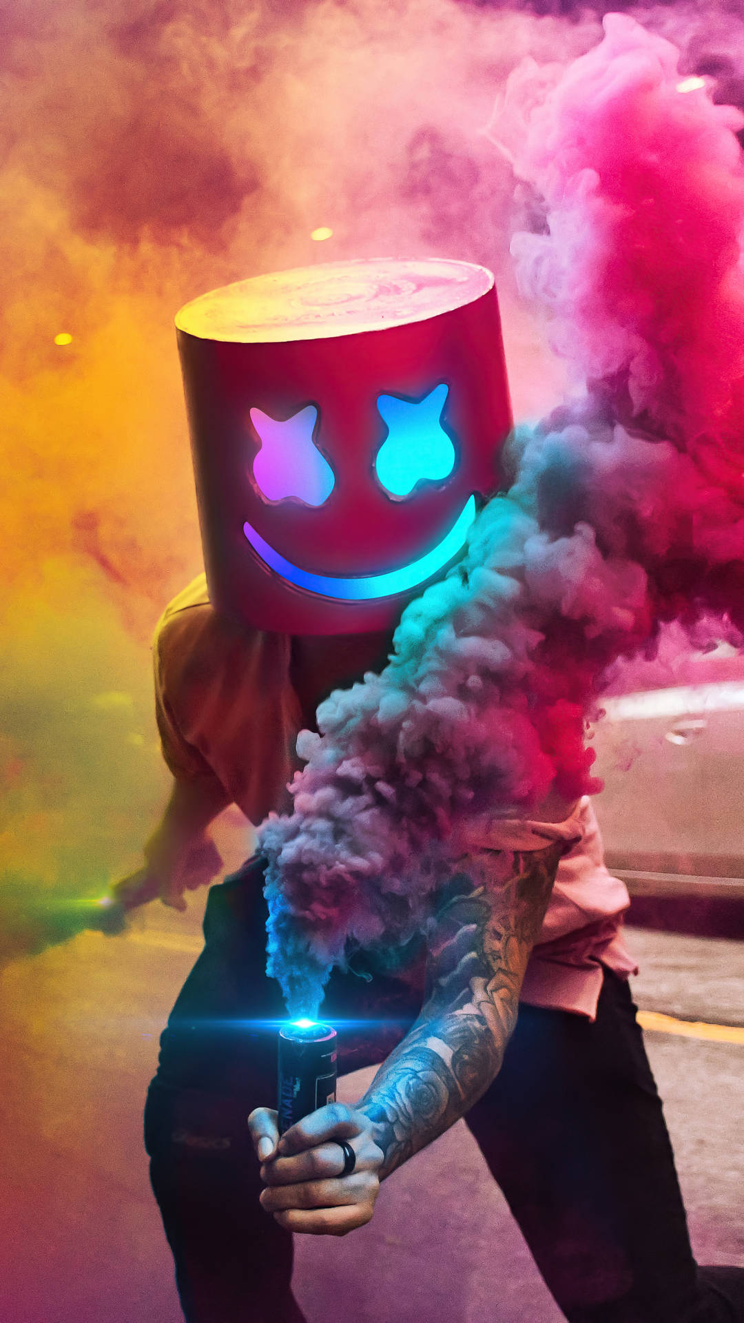 戴著發光Marshmello面具的人在夜晚釋放彩色煙霧。