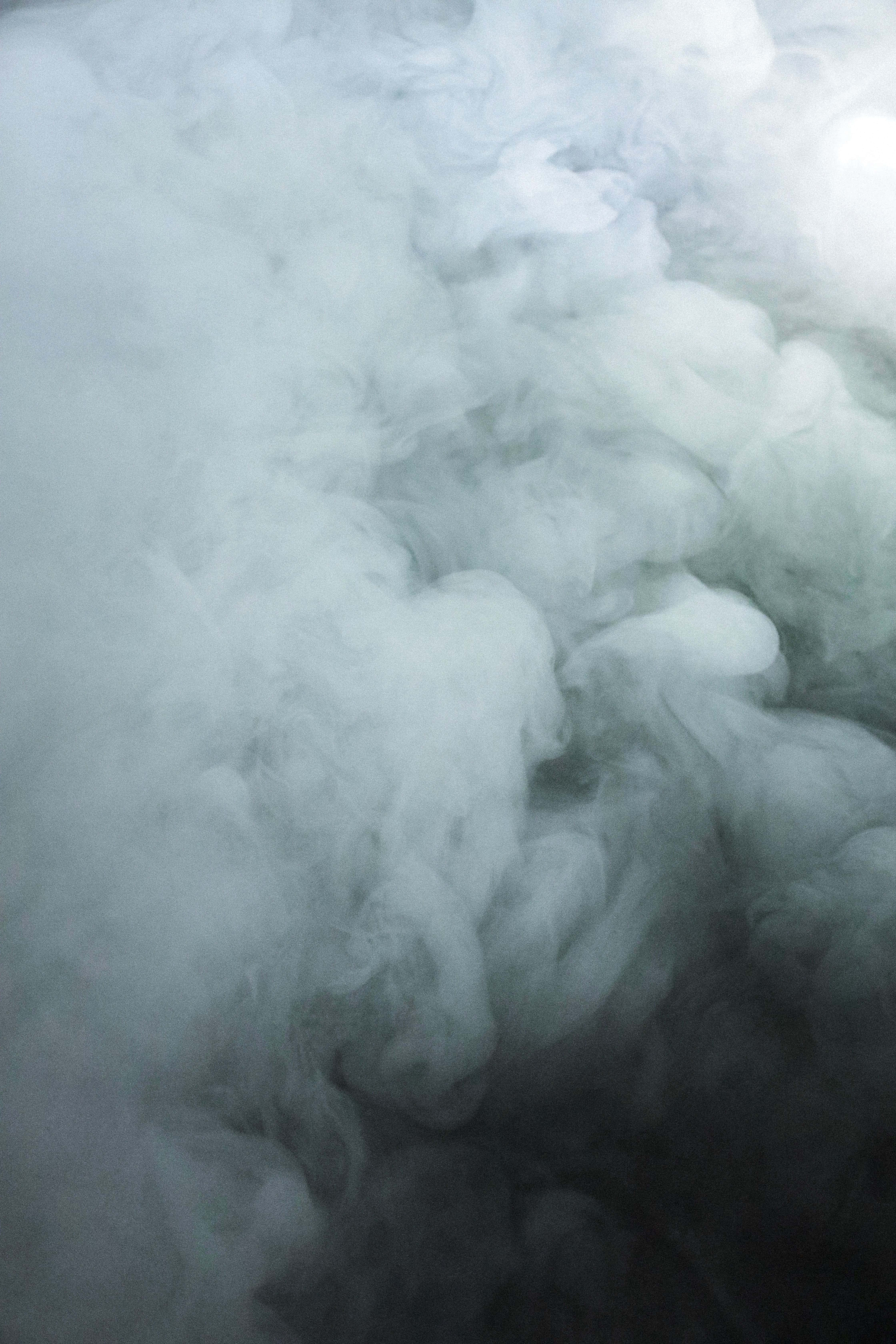 煙霧熊凝望的霧山日落 壁紙 — 一團冷色調的煙霧在黑暗背景上以白色和灰色的柔和漸變飄動。