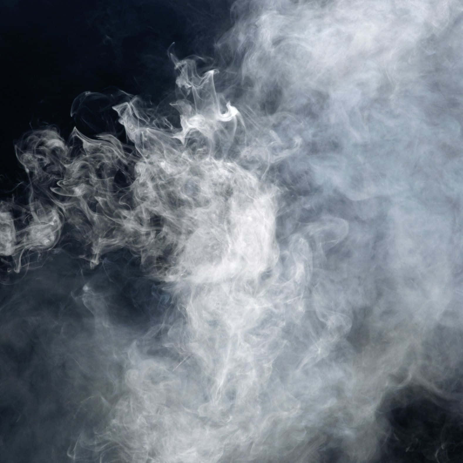 煙霧背景：幽靈白煙 壁紙 — 縹緲的白色煙霧在深邃的黑色背景中翻騰扭轉，營造出神秘而動感的抽象形態。