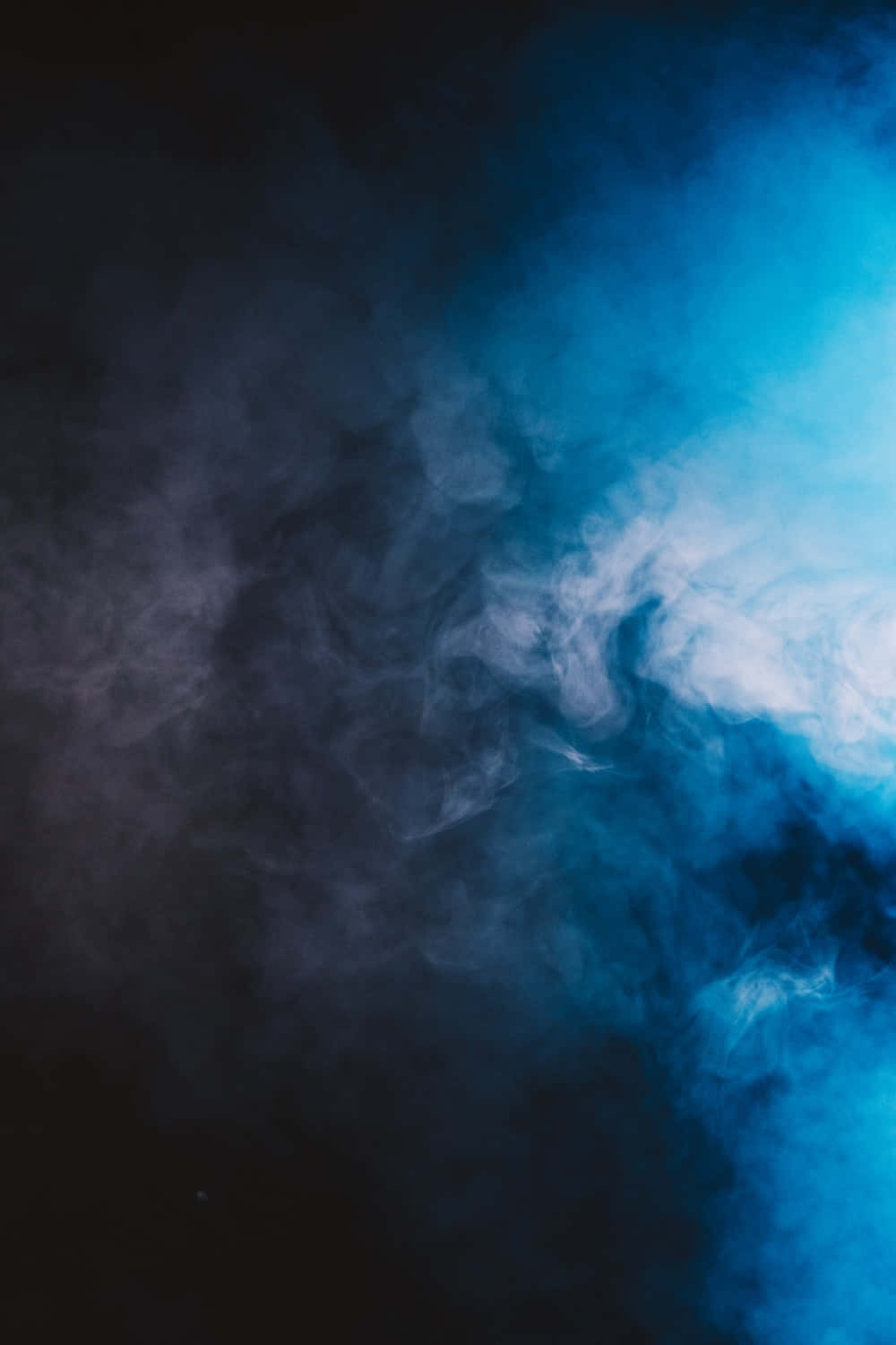 煙霧背景深藍色調 壁紙 — 豐盈的藍色和白色煙霧在深黑色背景下戲劇性地旋轉，營造出空靈而陰鬱的氛圍。