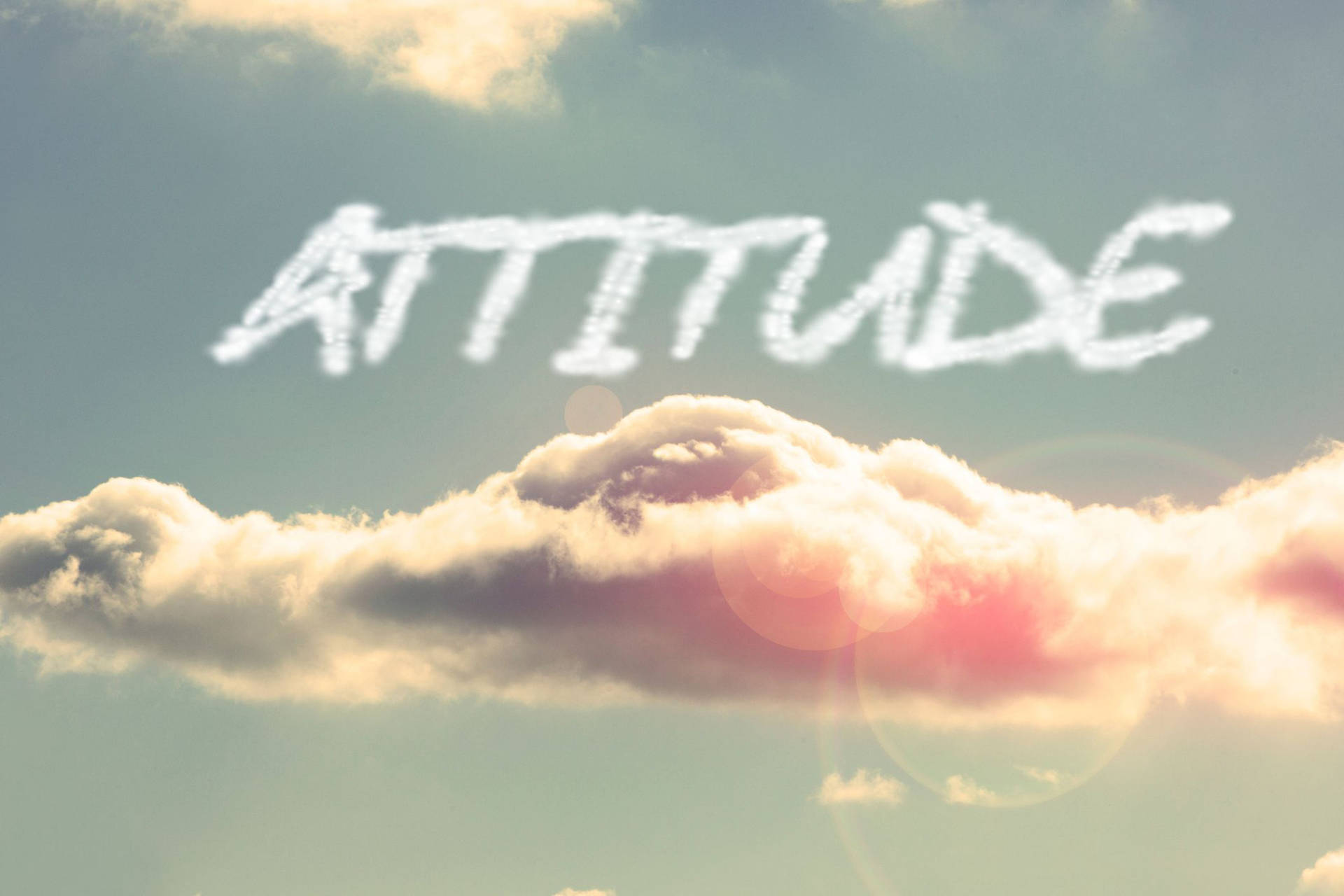 雲朵在天空中拼出「attitude」，帶有溫暖陽光和鏡頭光暈。