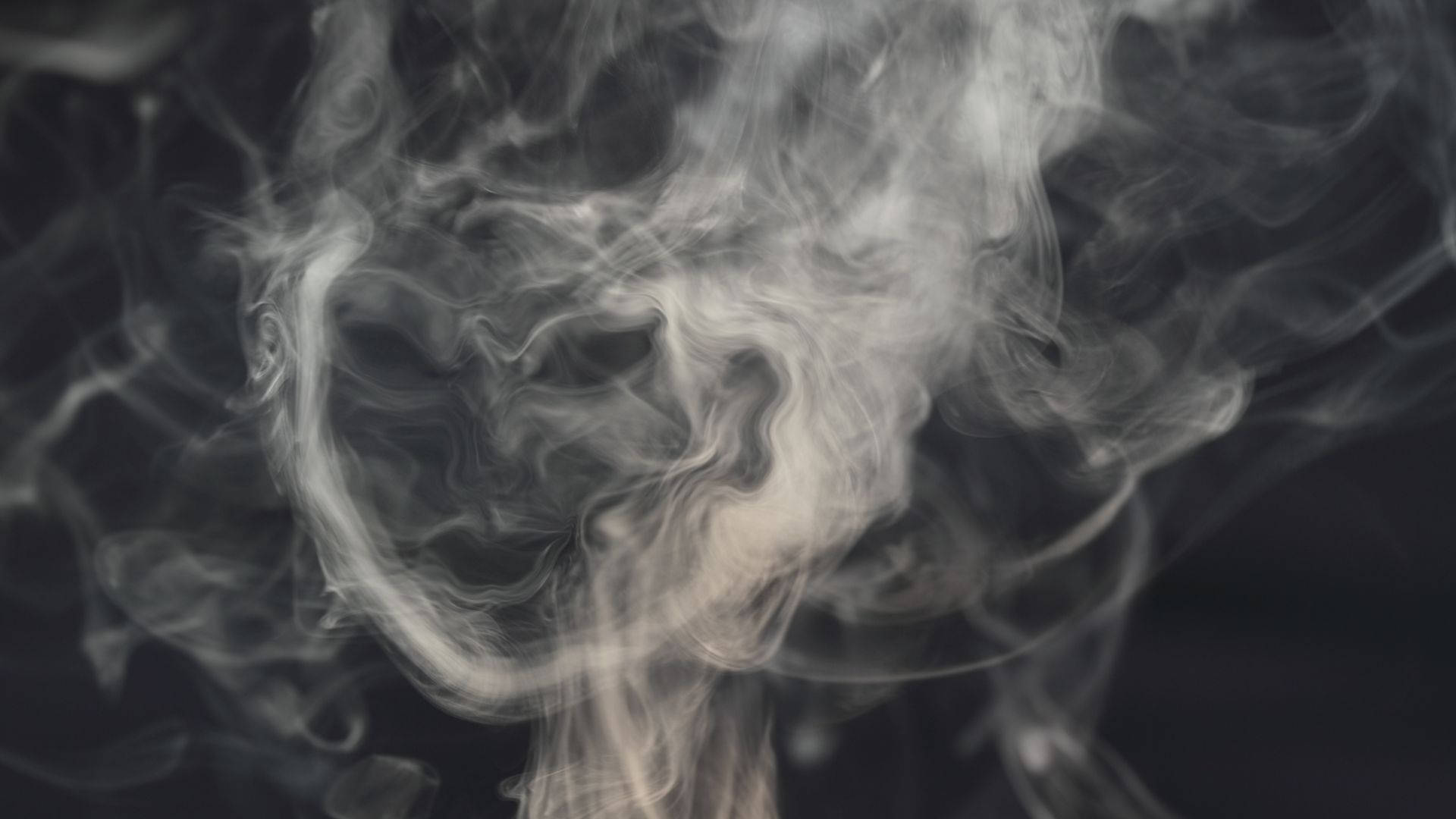 在黑暗背景上旋轉的白色煙霧