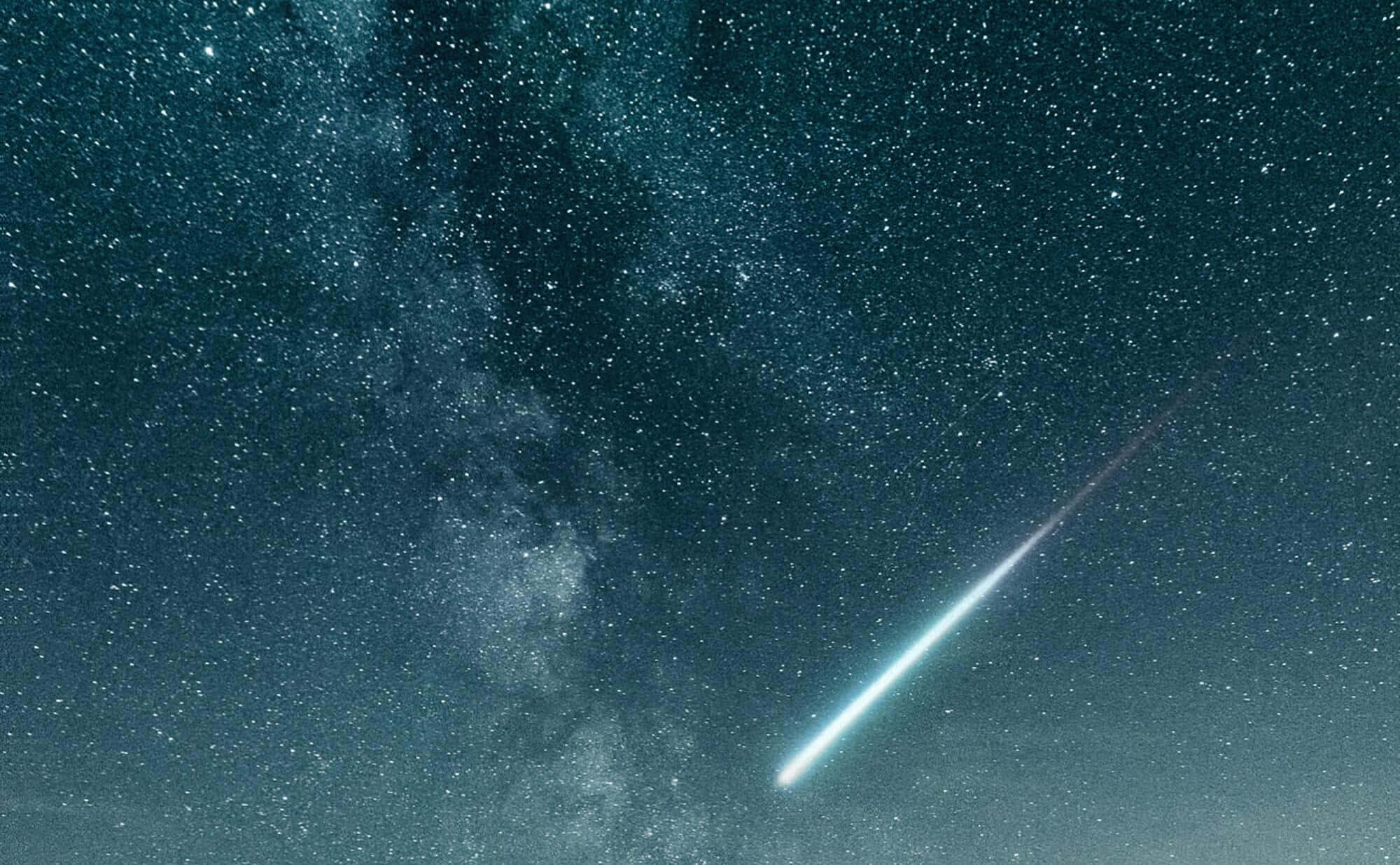 照亮天際：流星劃過大氣層 壁紙 — 一顆明亮的流星劃過繁星點點的夜空，銀河在深青色和靛藍色中閃耀。