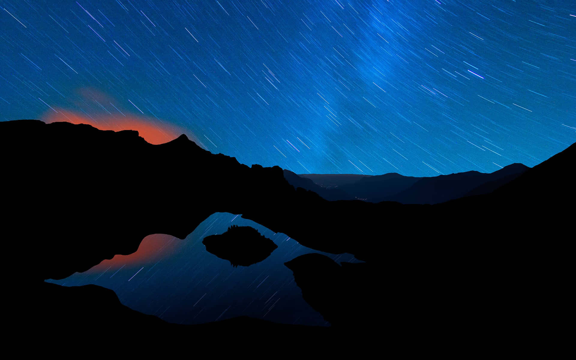 夜間山脈與湖泊上的星軌，伴隨著橙色極光。
