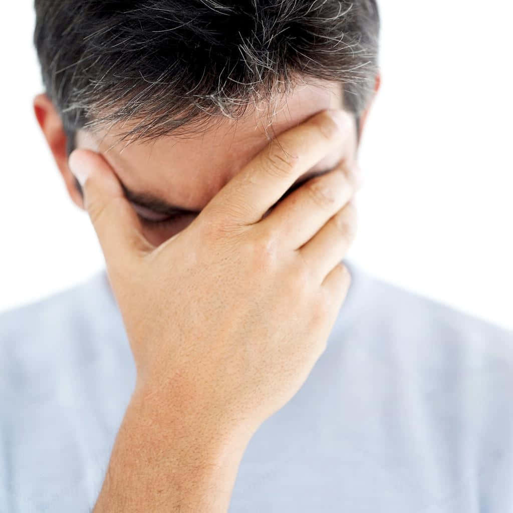 煩惱的男性 壁紙 — 一個頭髮灰白的男人用手遮住臉，背景是純白色。