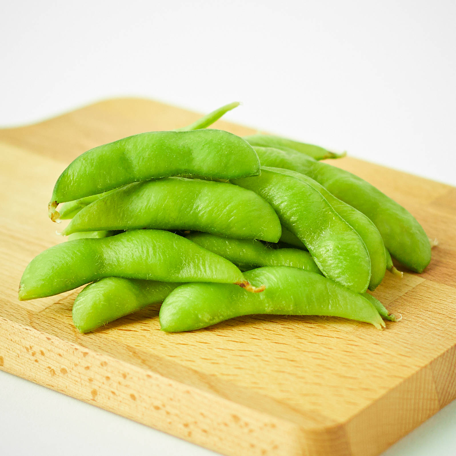 木砧板上的新鮮綠色毛豆莢。