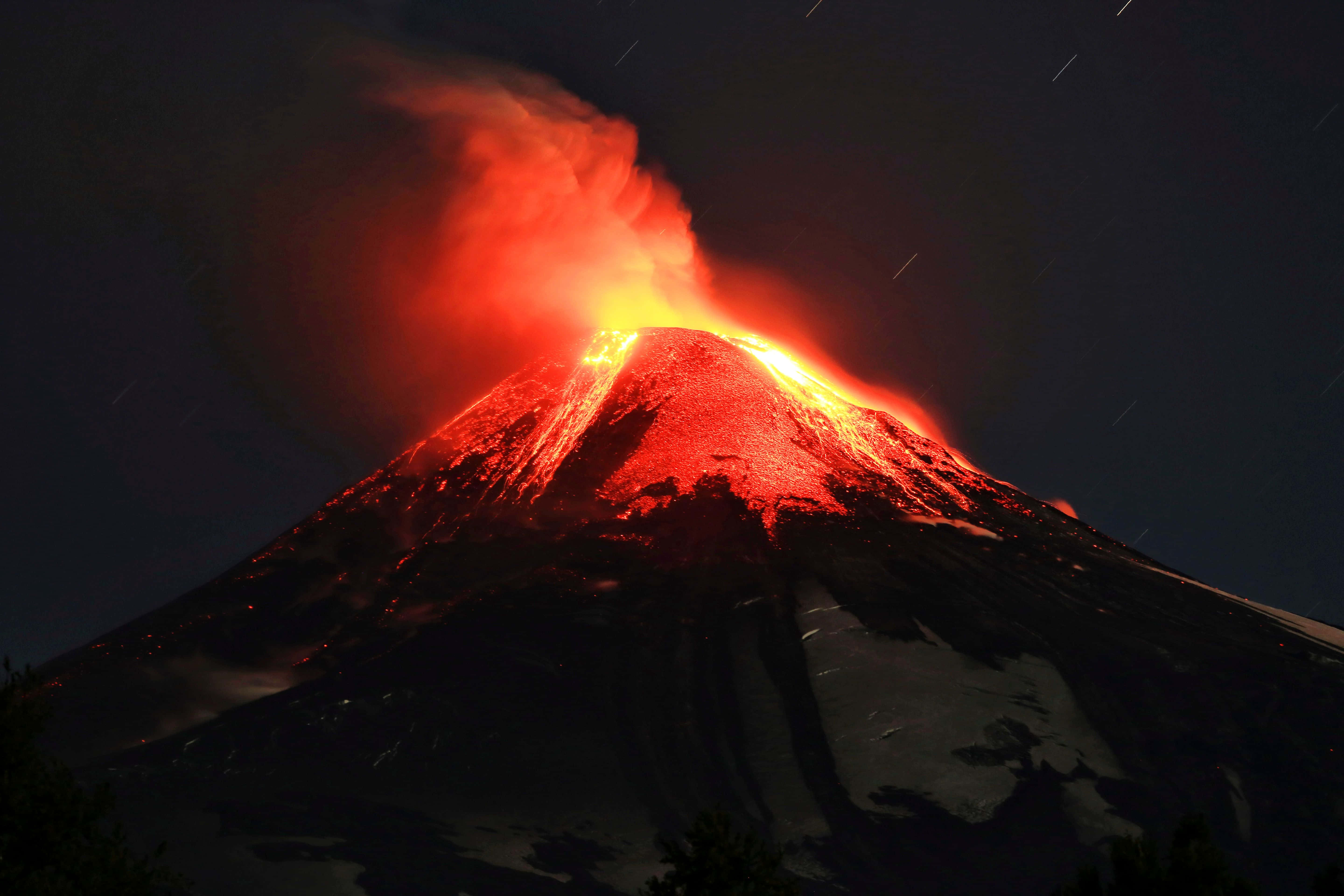 熔岩從火山頂噴發 壁紙 — 夜晚火山爆發，發光的熔岩和煙霧映襯著星空。