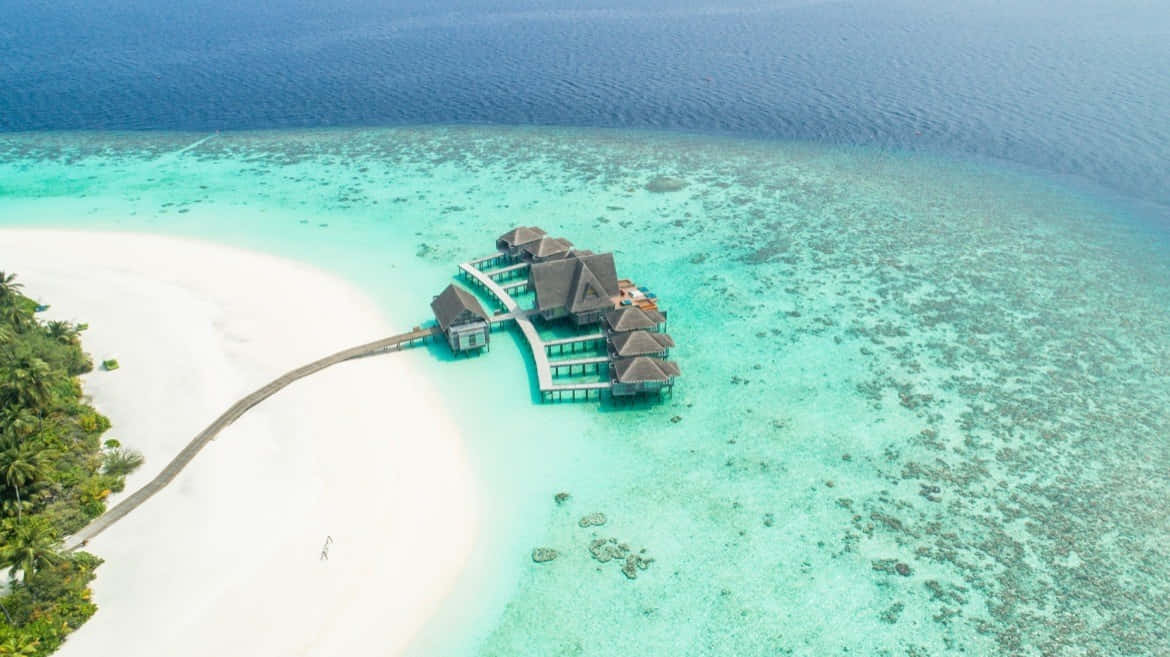 Maldives Island 桌布 壁紙 — 熱帶島嶼上豪華水上平房的鳥瞰圖，擁有碧綠色的潟湖和白色沙灘。