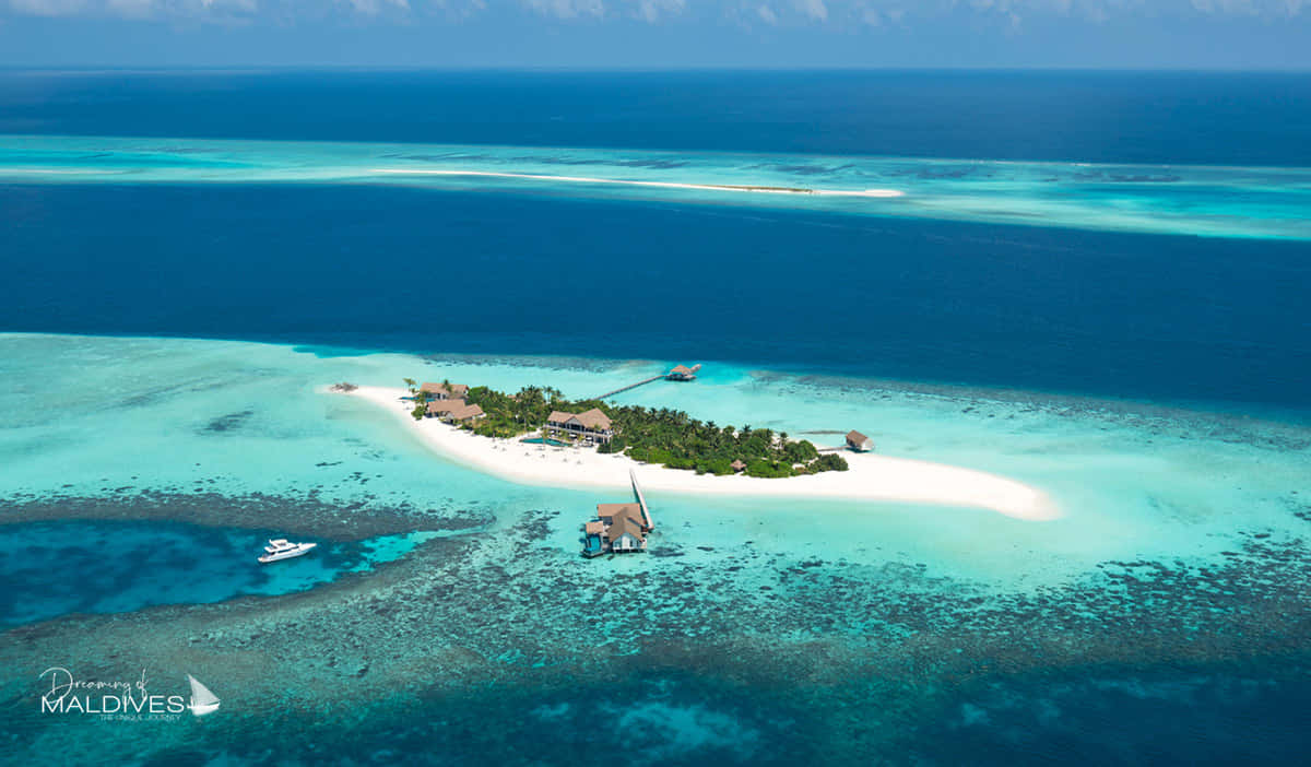 Maldives Island 桌布 壁紙 — 熱帶島嶼度假村的鳥瞰圖，擁有白色沙灘、碧綠潟湖和水上平房，四周環繞著深藍色海洋。