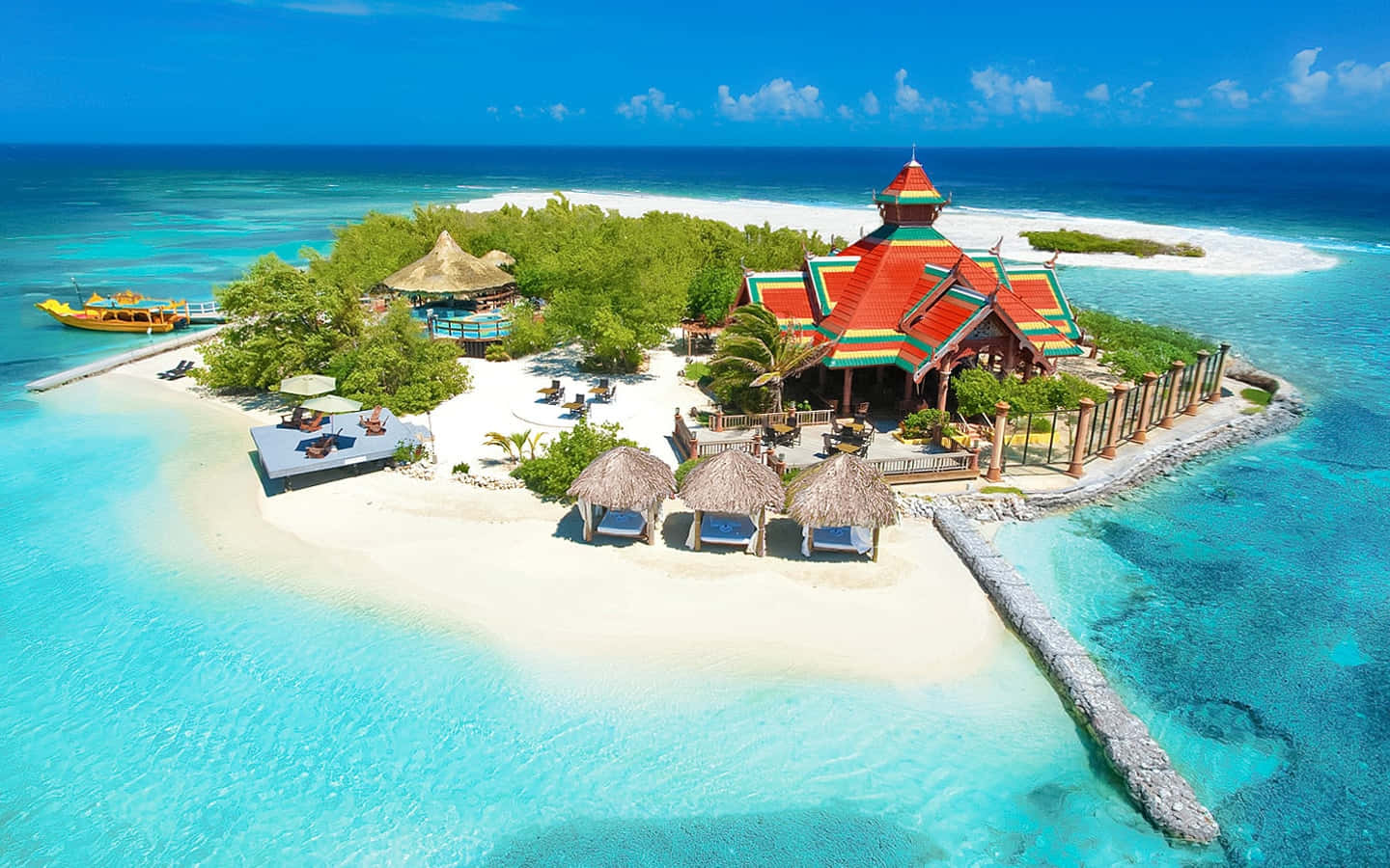 Jamaican Island 桌布 壁紙 — 熱帶島嶼度假村的鳥瞰圖，擁有色彩繽紛的泰式建築、碧綠海水和白色沙灘。