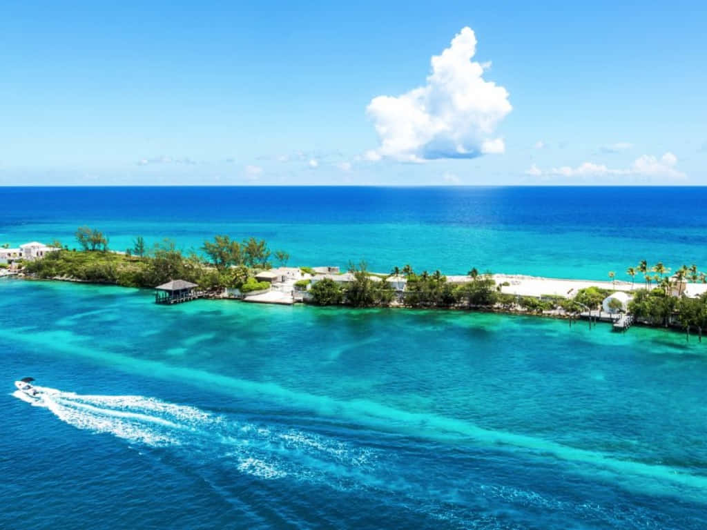 Bahamas Island 桌布 壁紙 — 熱帶島嶼的鳥瞰圖，擁有碧綠的海水，一艘快艇在明亮的藍天下劃過海面。