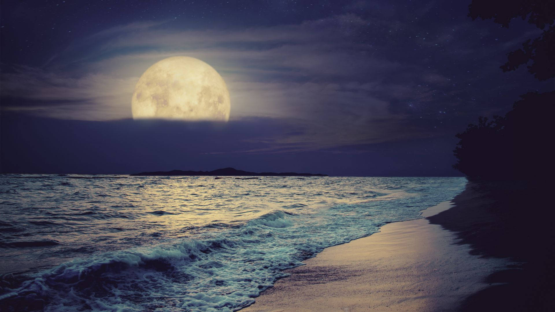 夜晚平靜海洋上的滿月與沙灘上的海浪