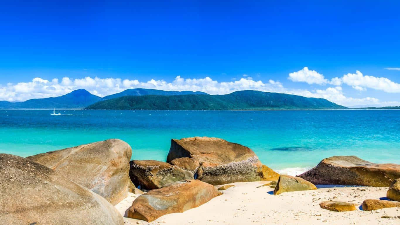 熱帶海灘，有碧綠的海水和巨大的岩石，在明亮的藍天下。