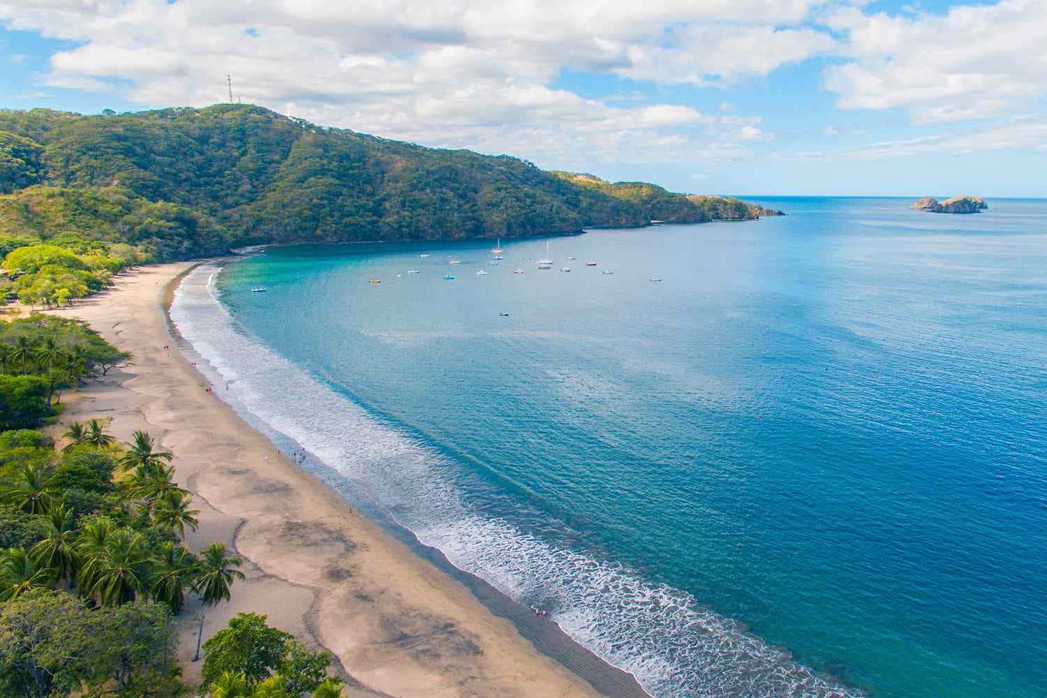 Costa Rica 桌布 壁紙 — 熱帶海灘的鳥瞰圖，碧綠的海水、溫柔的海浪和鬱鬱蔥蔥的綠色山丘環繞著海岸線。