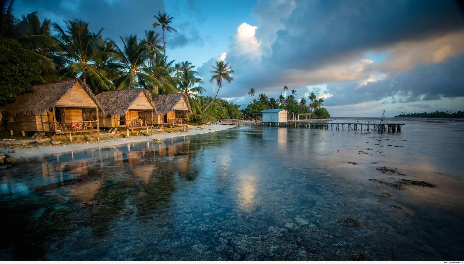 熱帶海灘茅草屋頂小屋在平靜的碧綠海水中倒映，天空暮色壯麗。