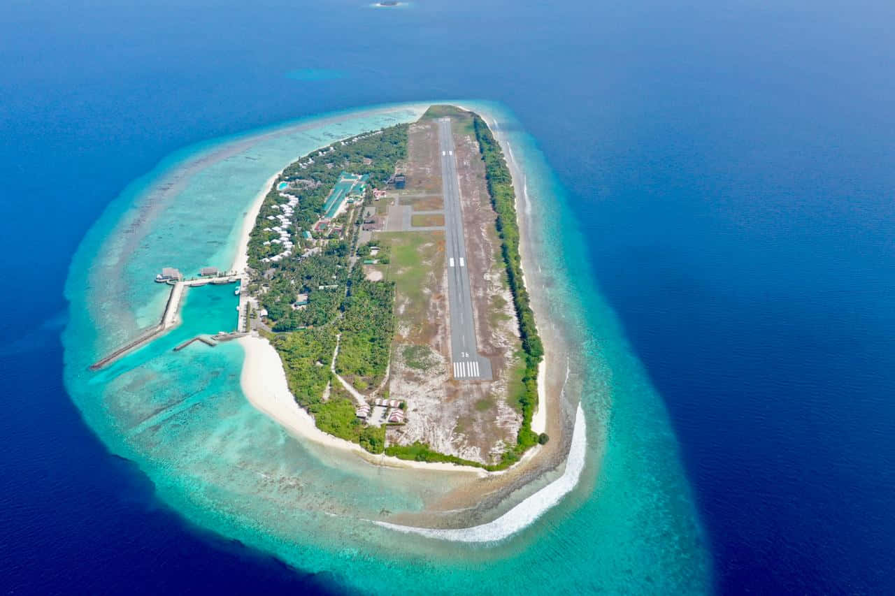 Maldives Island 桌布 壁紙 — 熱帶環礁島嶼的鳥瞰圖，跑道穿過茂密的綠植和碧綠色的潟湖。