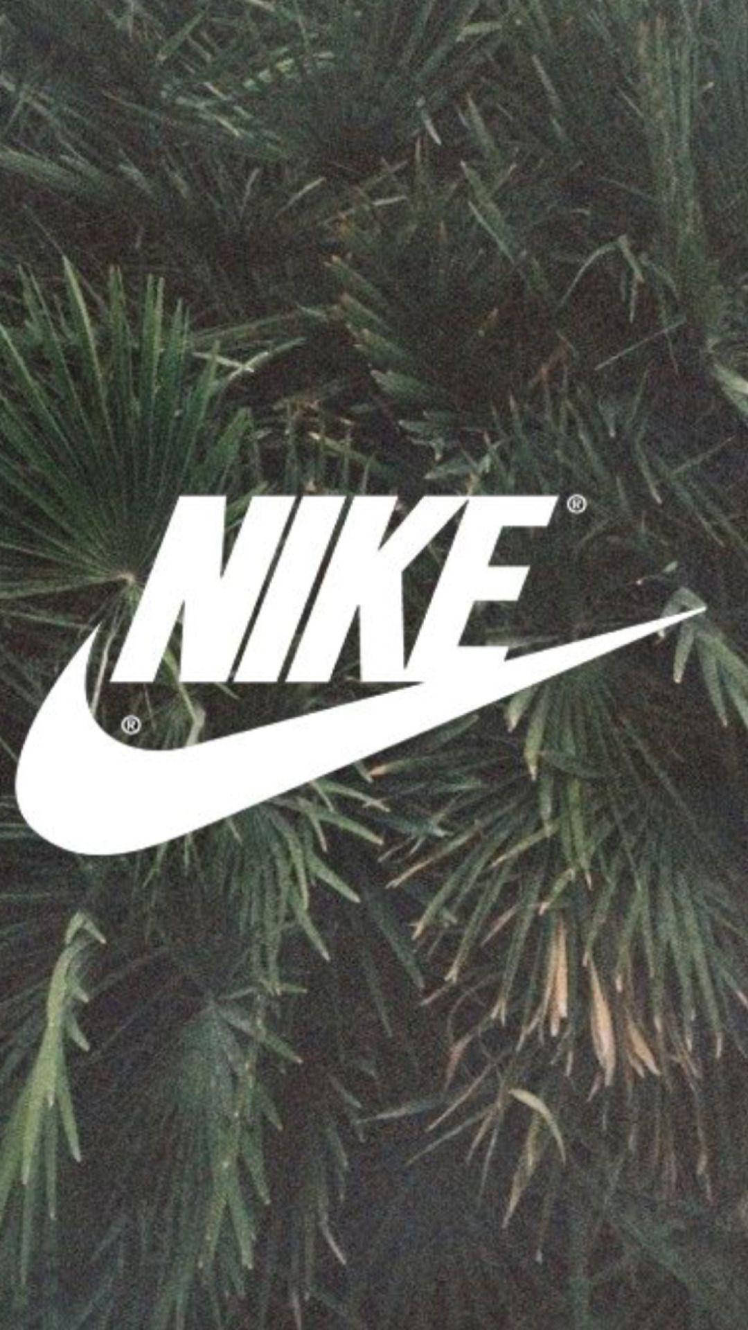 熱帶風 Nike iPhone 背景 壁紙 — 大膽的白色Nike標誌覆蓋在密集的深綠色棕櫚葉上，形成粗糙紋理的壁紙。