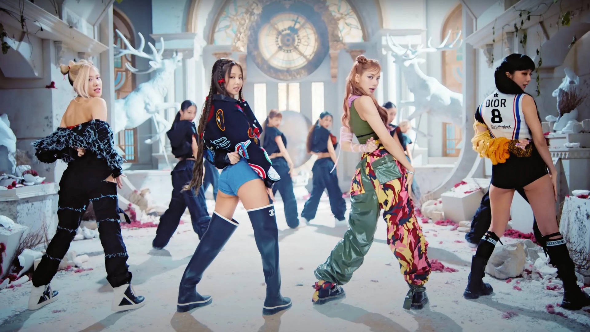 K-pop 舞者穿著色彩繽紛的服裝，在雪地大教堂中與發光的鹿雕像合影。