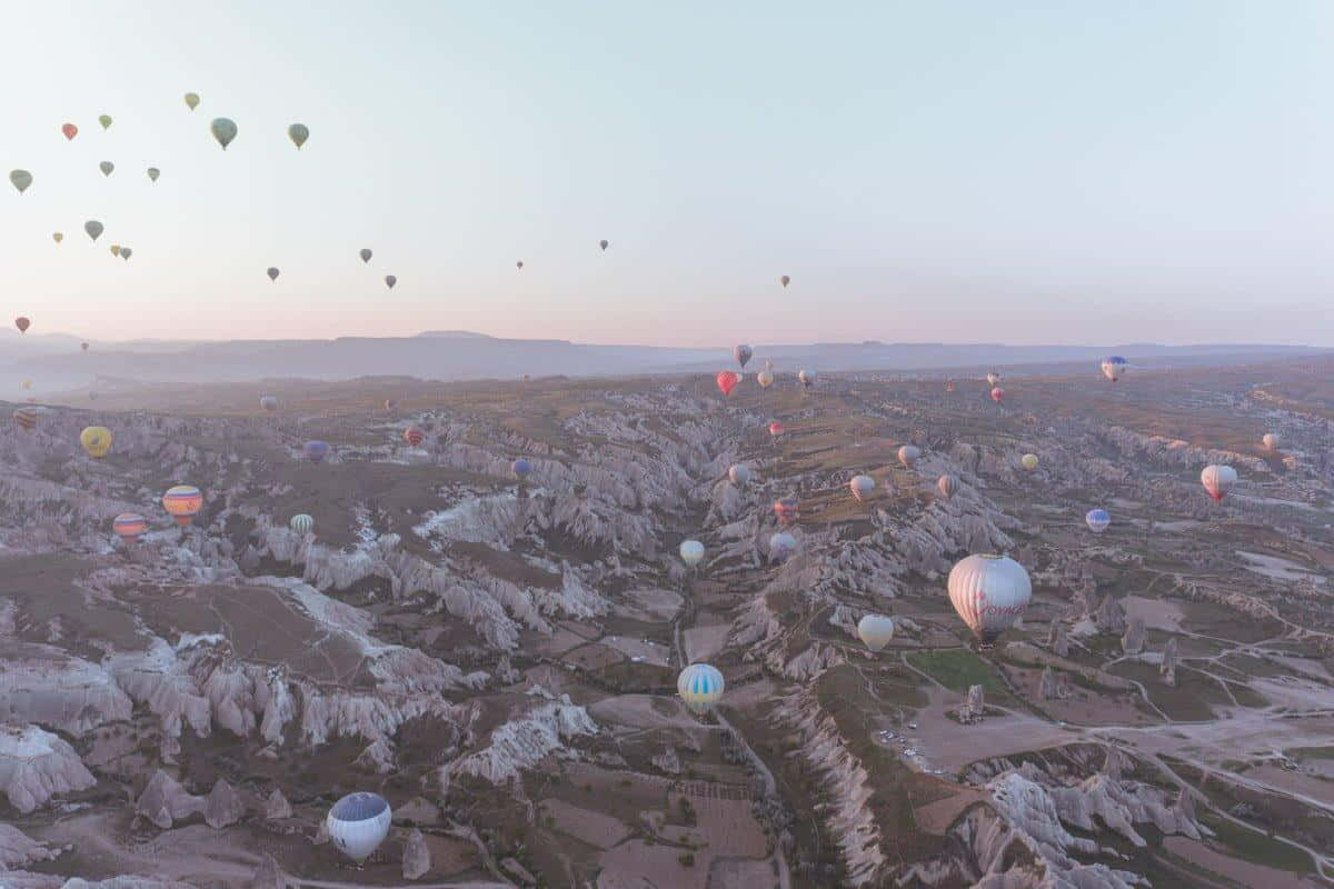 Hot Air Balloon 桌布 壁紙 — 熱氣球在卡帕多奇亞的黎明時分飄過超現實的岩石地貌。