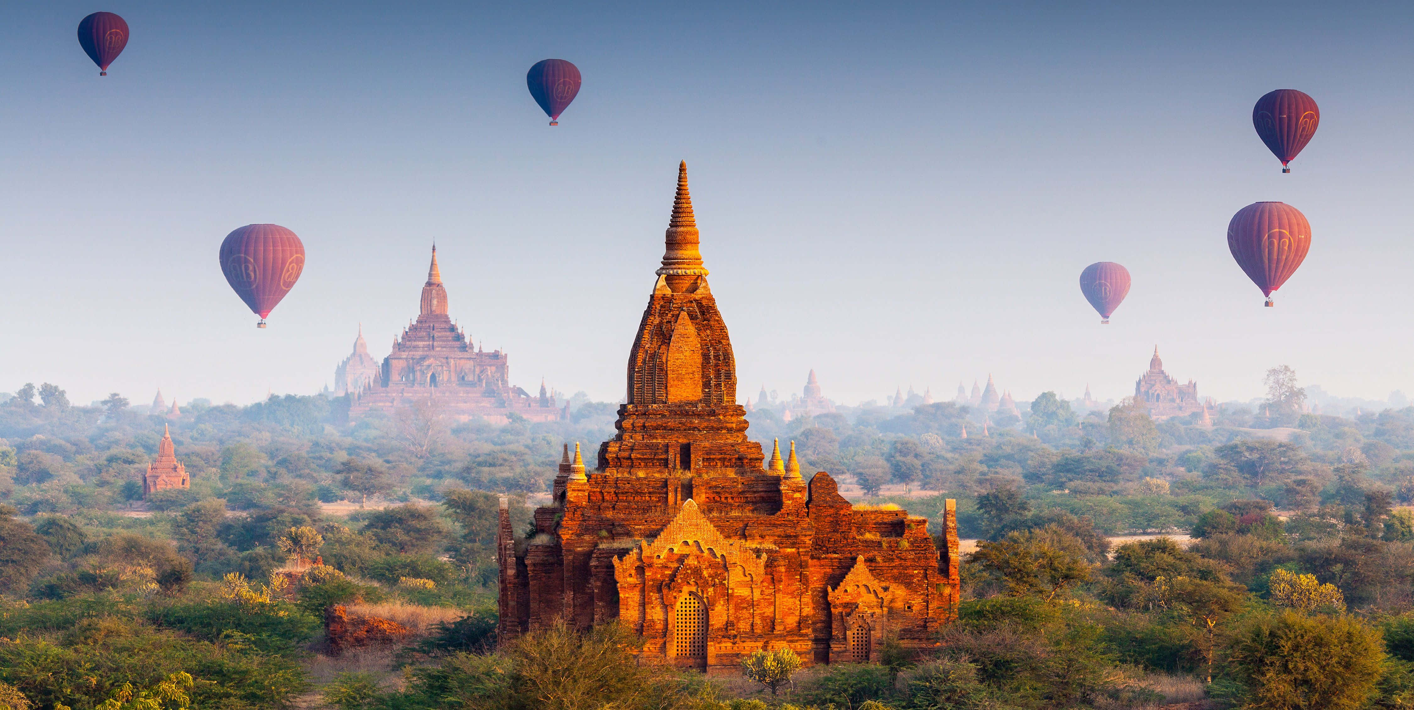 Hot Air Balloon 桌布 壁紙 — 熱氣球在日出時飄過翠綠山谷中古老的金色寶塔。