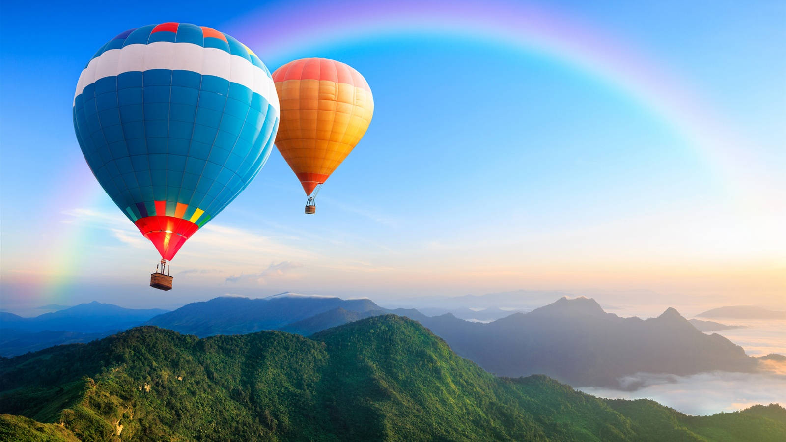 兩個熱氣球漂浮在山脈上空，天空中有彩虹。