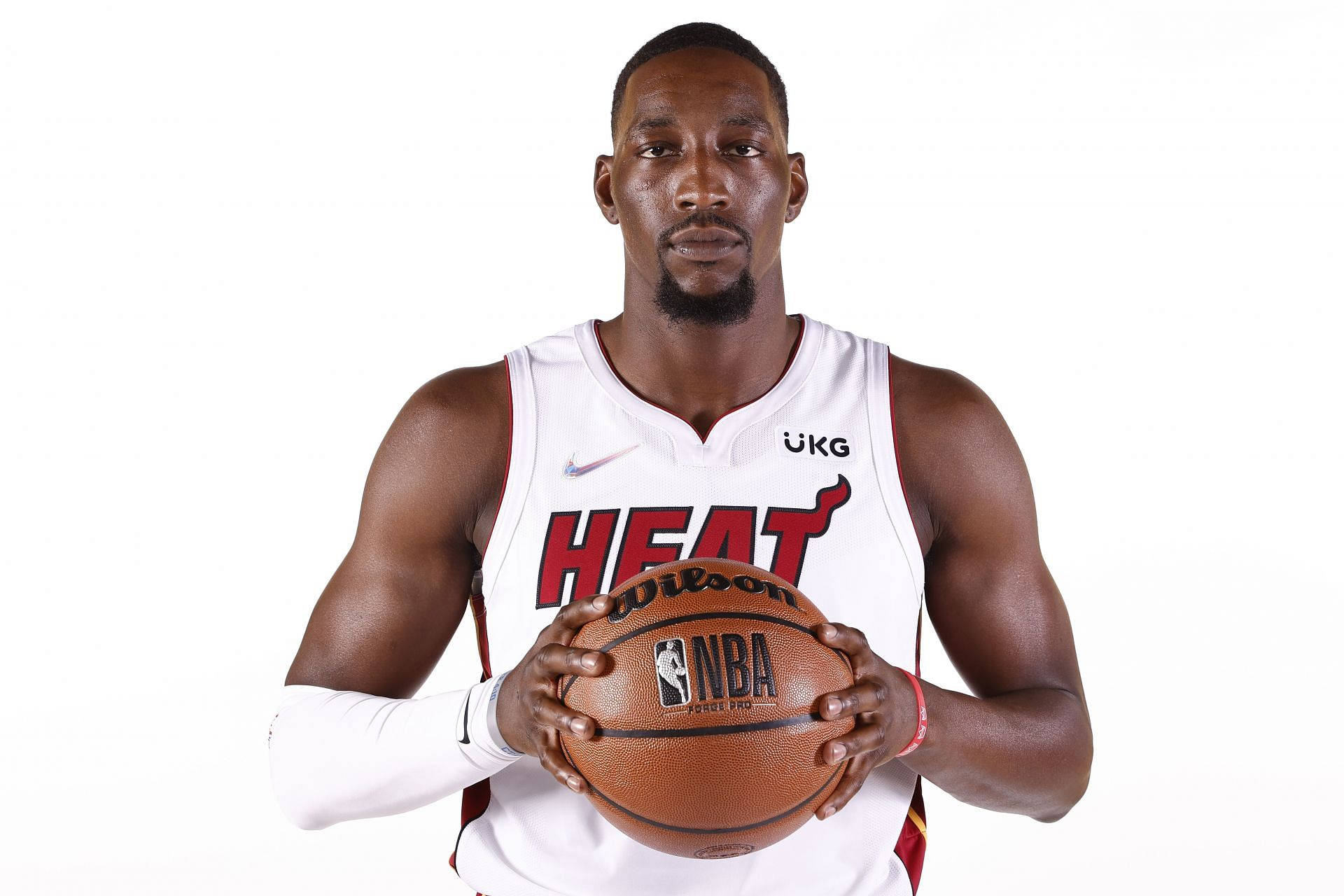 熱火隊 Bam Adebayo 白色背景 壁紙 — 一位專注的籃球運動員身穿白色邁阿密熱火球衣，在純白背景下拿著一個棕色的Wilson NBA籃球。