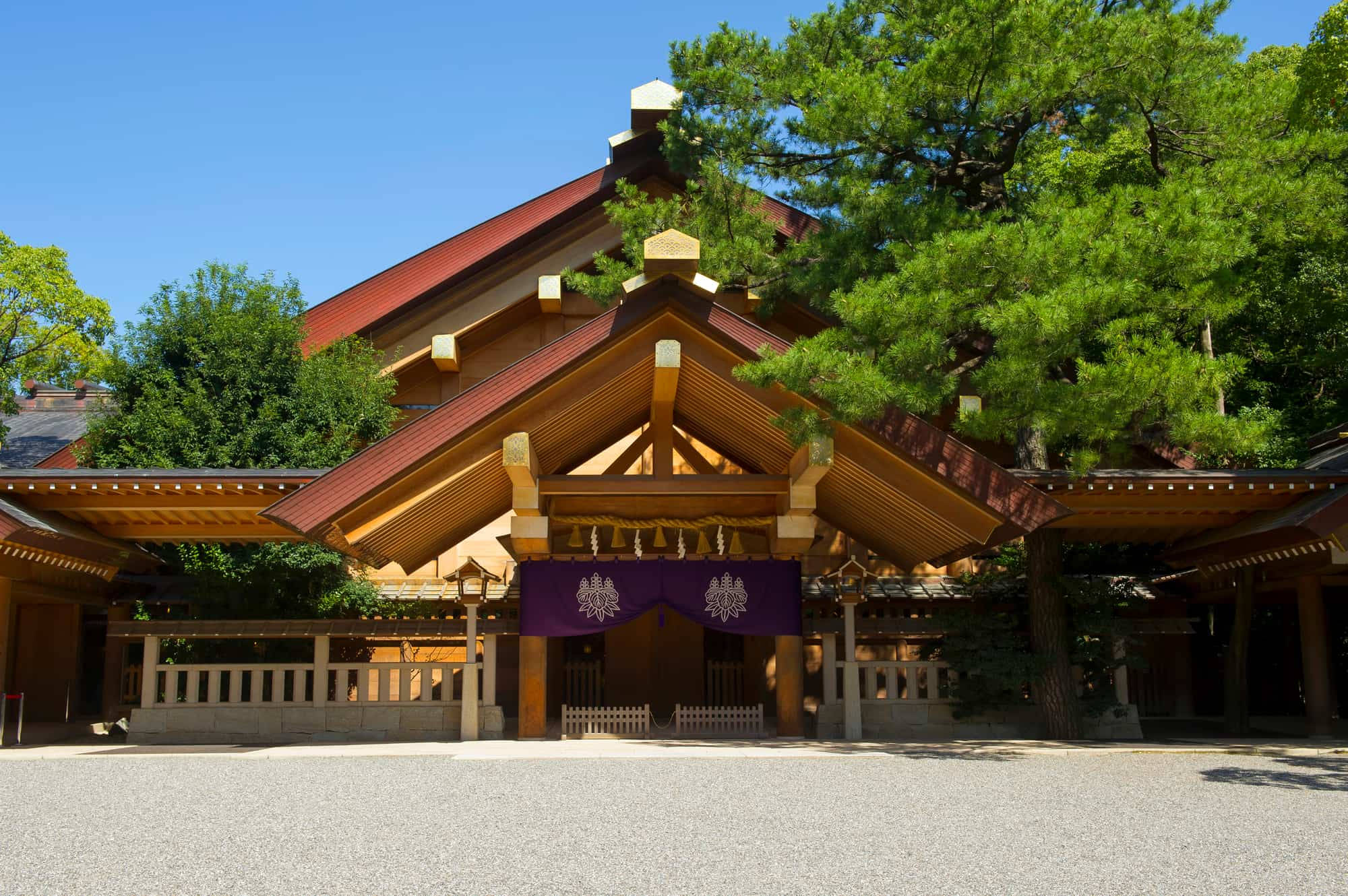 熱田神社：名古屋的文化盛景 壁紙 — 傳統日本神社，木造建築與紅色屋頂，被茂密綠樹環繞，天空清澈湛藍。