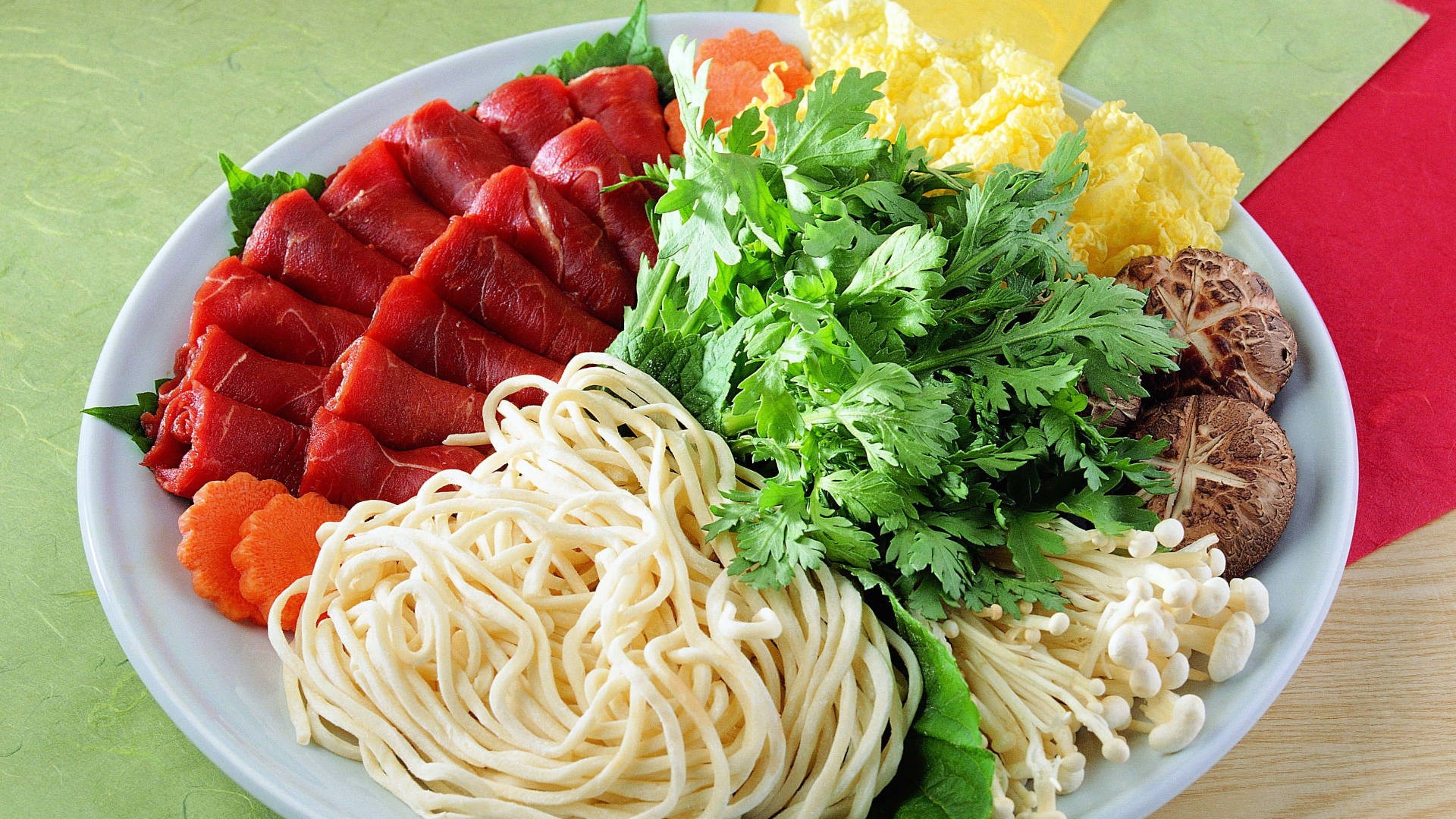 熱鍋意麵與食材 壁紙 — 一碗色彩鮮豔的生牛肉片、麵條、蘑菇和青菜整齊排列，適合火鍋。