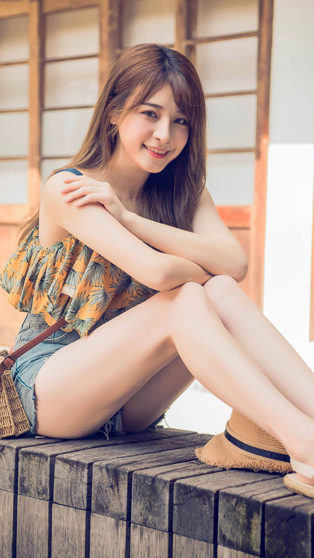 年輕女性坐在戶外木長椅上微笑。
