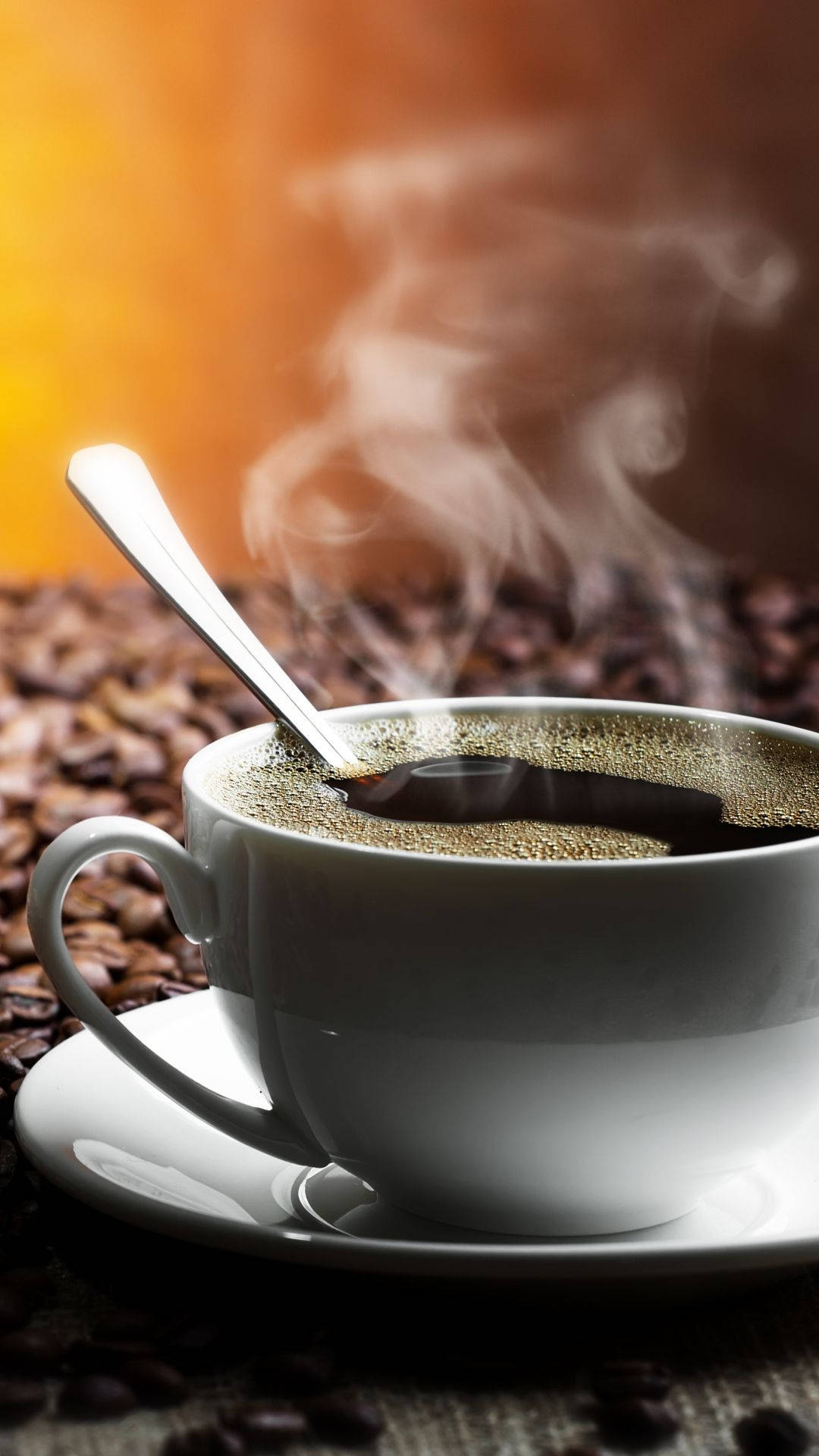 熱騰騰深色咖啡杯 壁紙 — 一個冒著蒸氣的白色咖啡杯連湯匙放在碟子上，周圍是深烘焙咖啡豆，背景是溫暖的橙色漸變。