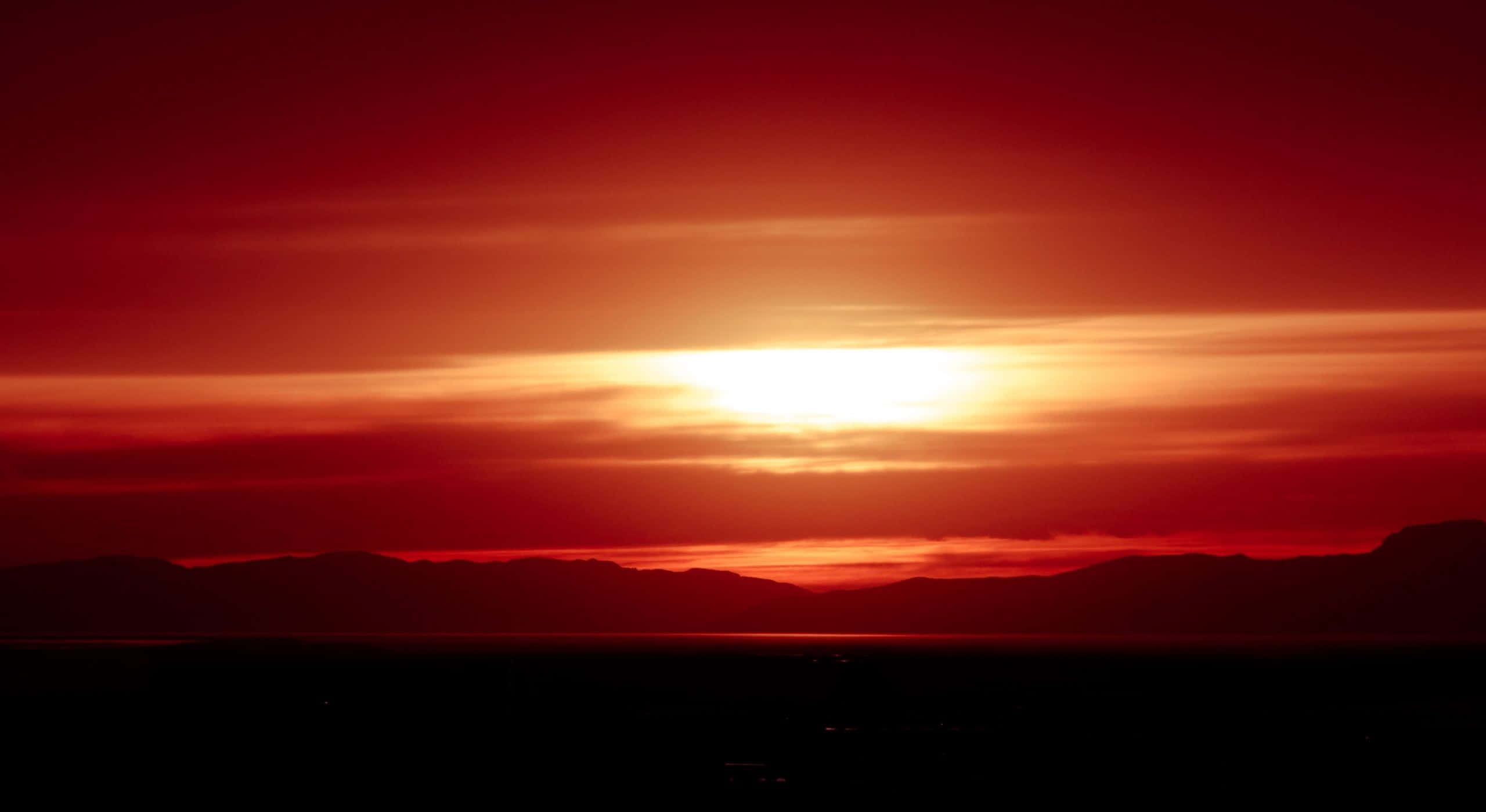 Red Sunset 桌布 壁紙 — 熾熱的夕陽在剪影般的山脈和寧靜的地平線之上，將天空染成深紅和橙色。