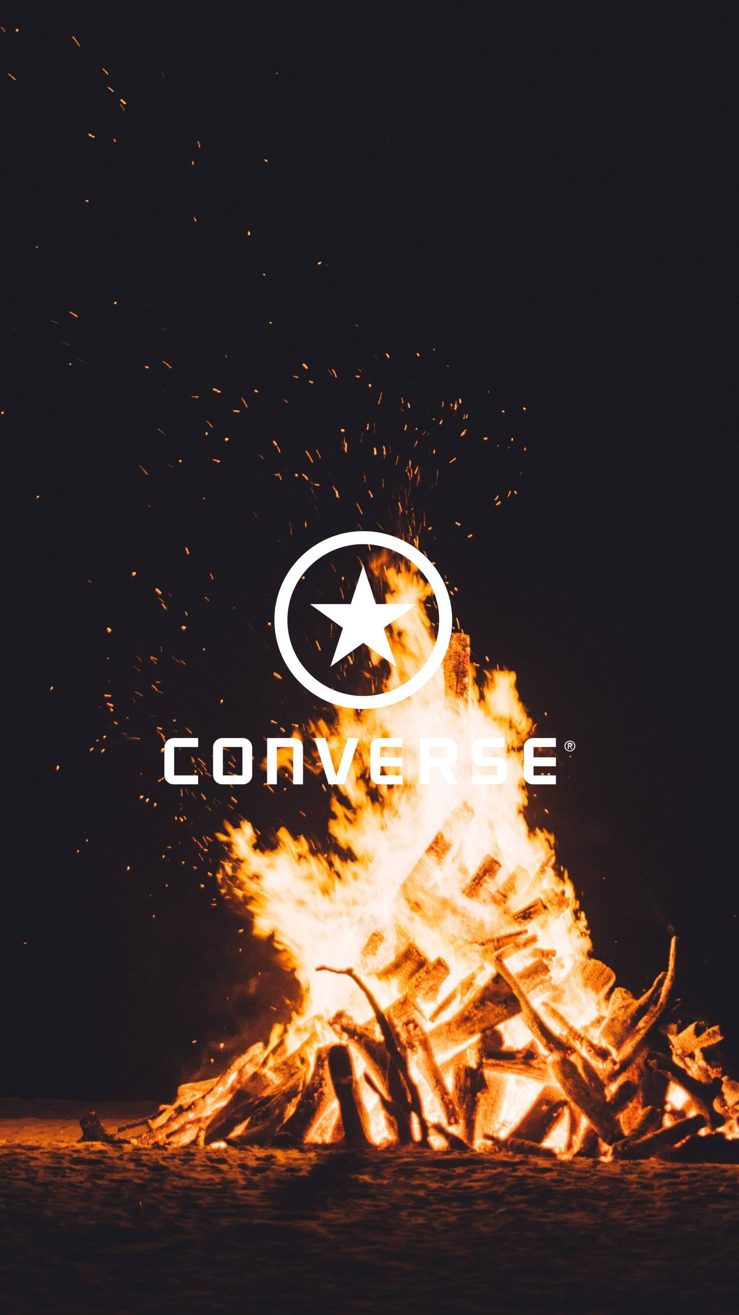 燃燒的Converse標誌 壁紙 — 夜晚咆哮的營火，火花飛舞，白色Converse標誌疊加在火焰上。