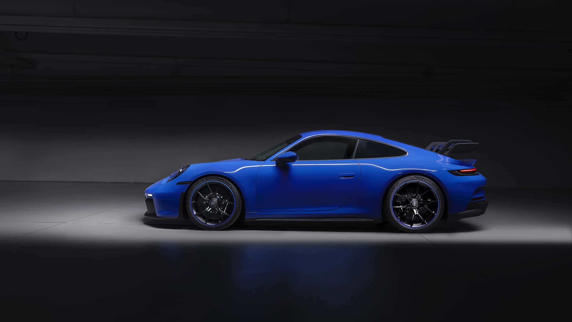 藍色保時捷 911 GT3 RS 在暗色攝影棚中，聚光燈照射。