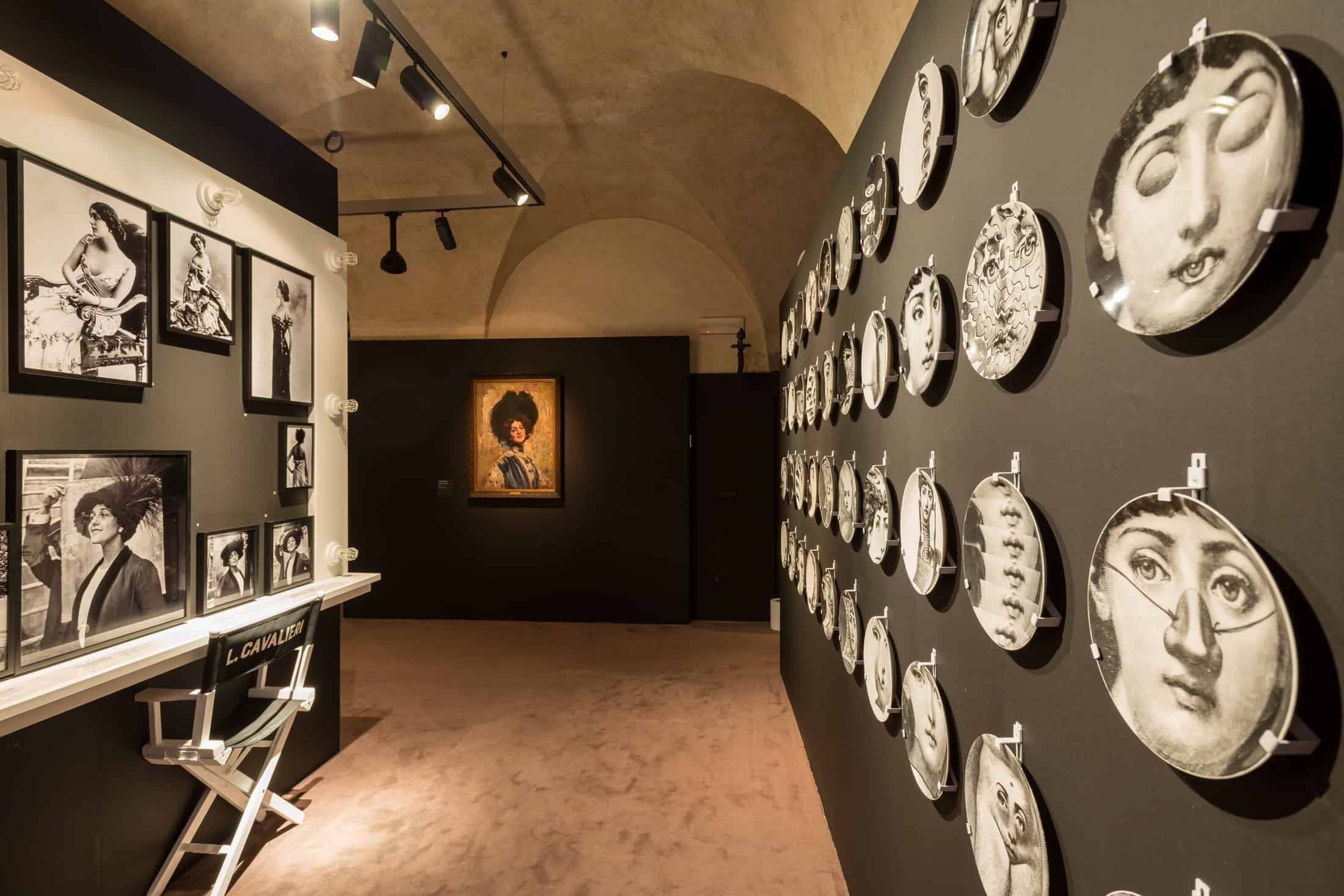 Museo Salvatore Ferragamo 壁紙 — 燈光昏暗的畫廊走廊，黑色牆壁展示著裝裱的黑白肖像和圓形臉部藝術品，置於聚光燈下。