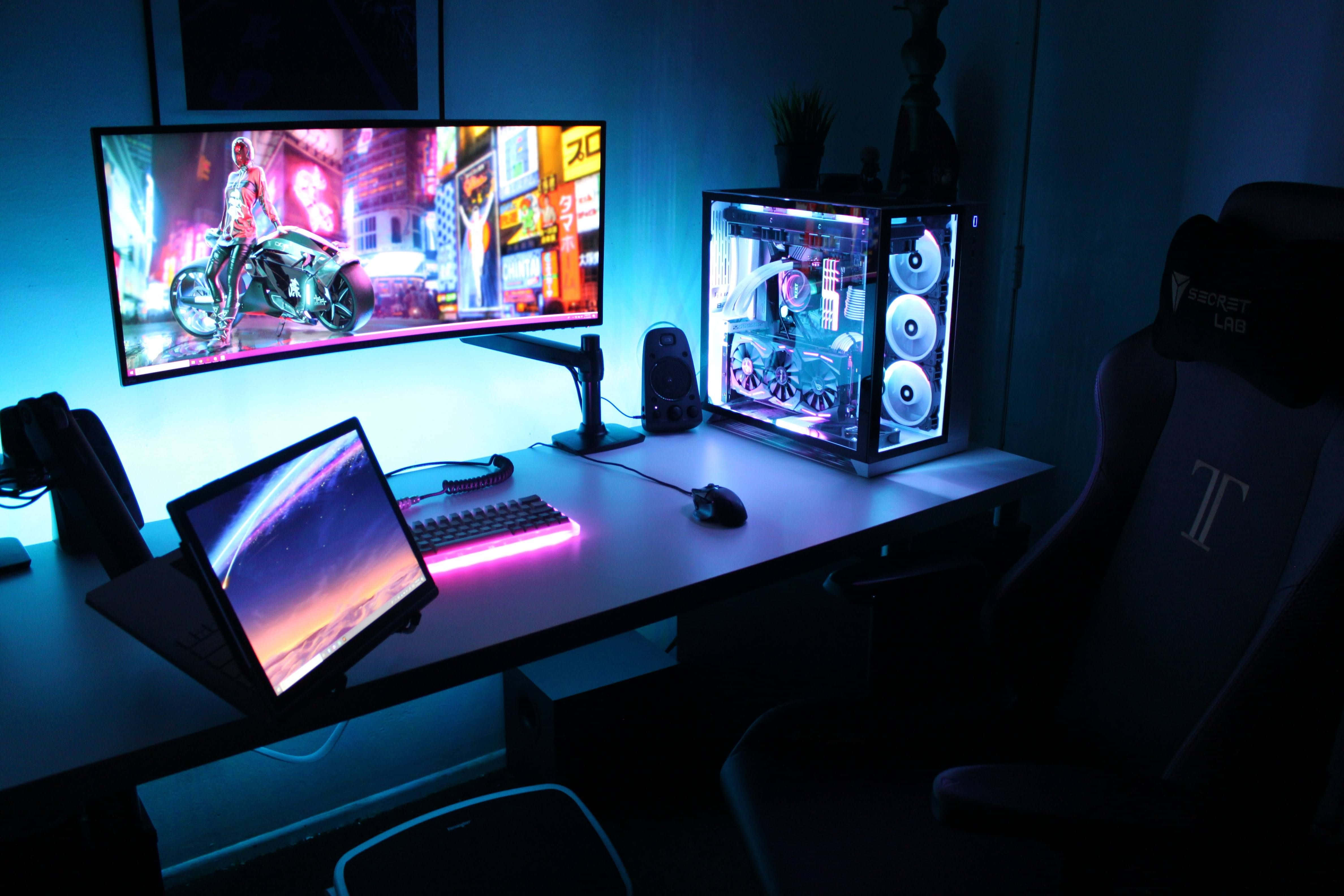 Gaming Pc Setup 桌布 壁紙 — 燈光昏暗的遊戲設置，配備曲面顯示器顯示霓虹燈電單車遊戲、發光RGB鍵盤和帶內部照明的透明PC機箱。