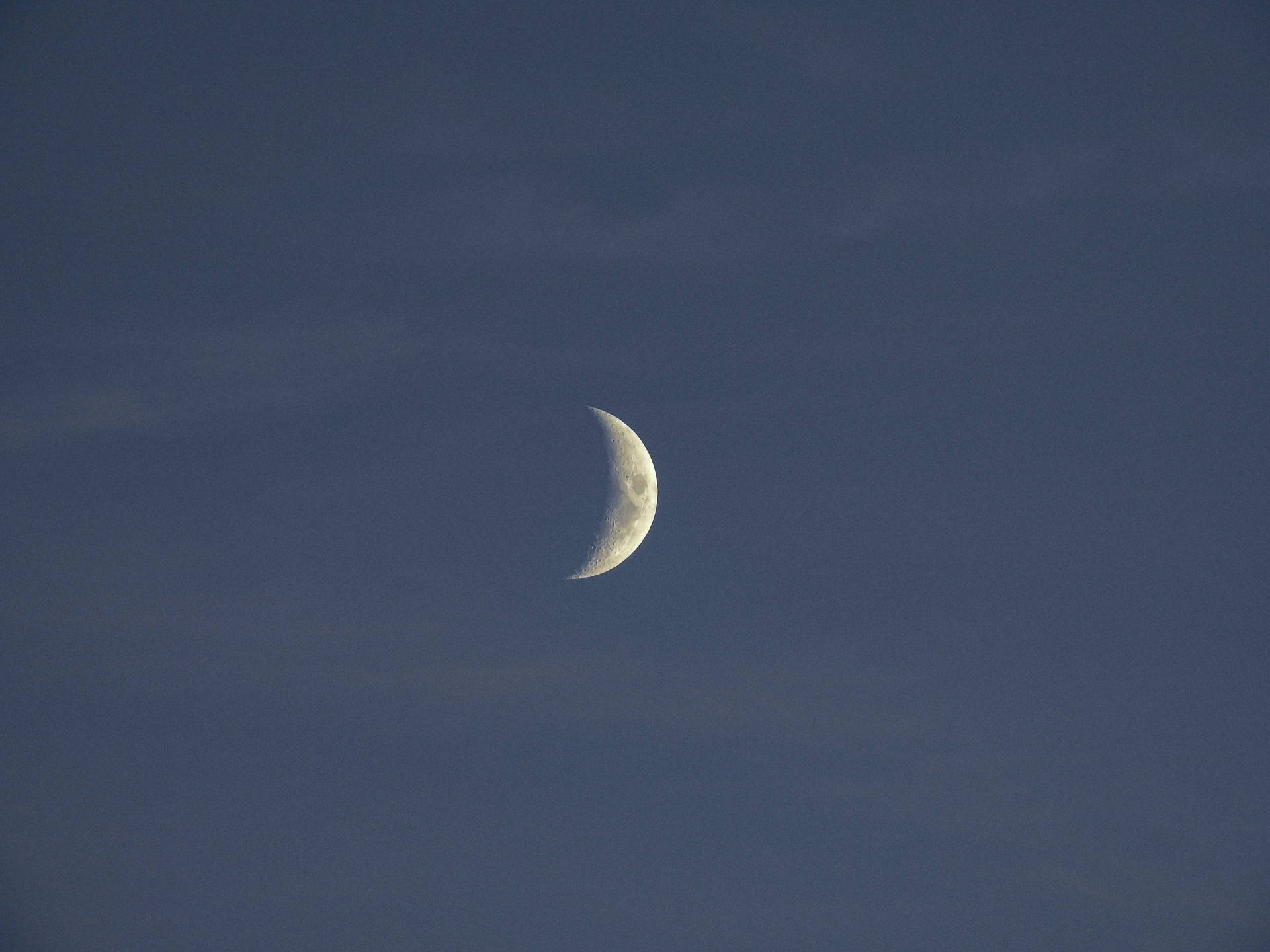 月牙在昏暗的藍色天空中閃耀，伴有輕柔的雲彩。