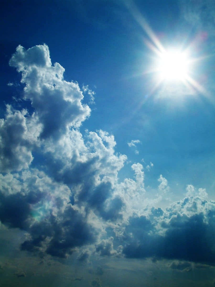 Blue Skies 桌布 壁紙 — 燦爛的太陽透過充滿蓬鬆白色和深藍色雲朵的動態天空散發出明亮的光芒。