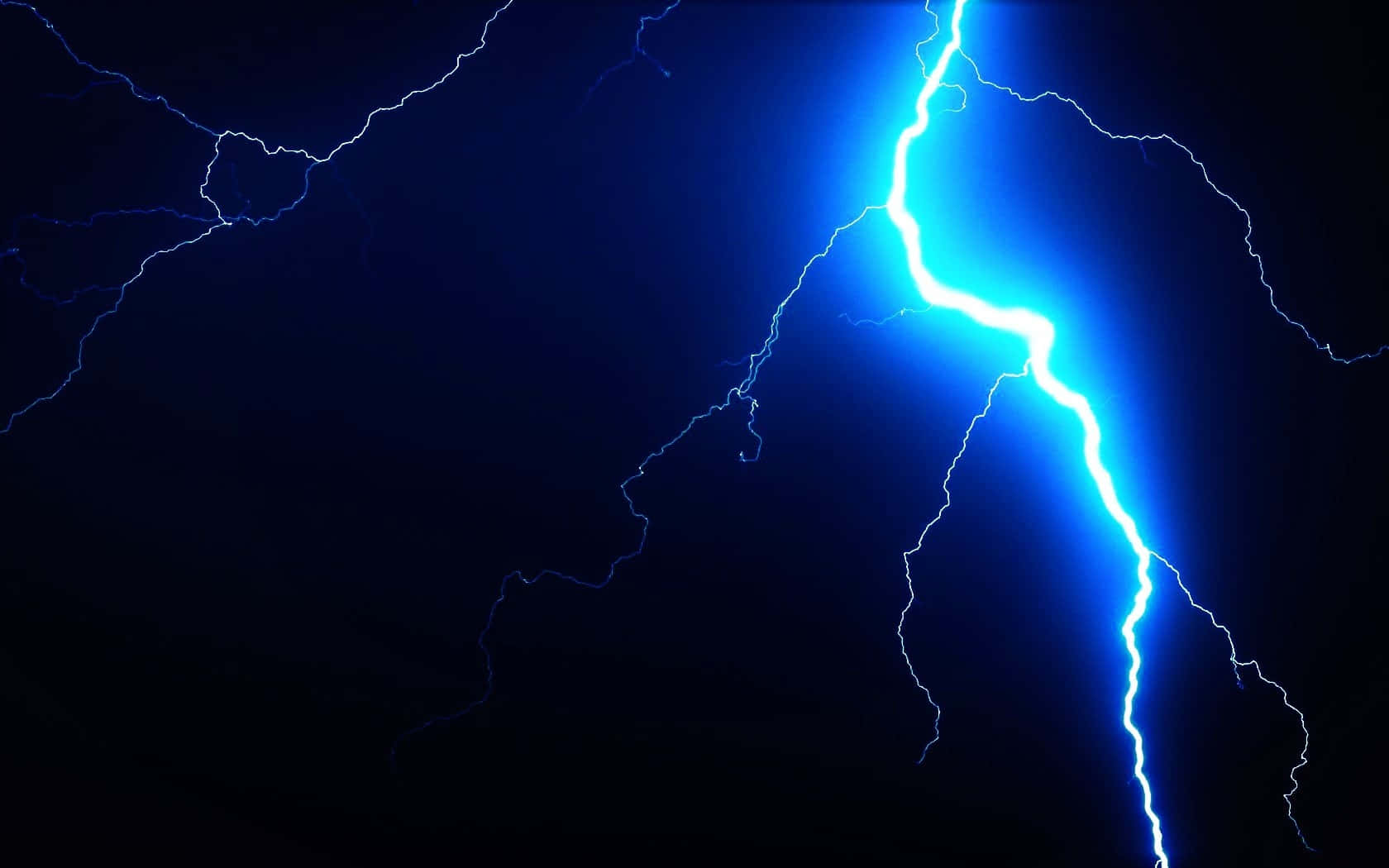 爆炸性閃電照亮夜空 壁紙 — 一道強大的藍色閃電在漆黑的天空中分叉，展現出戲劇性的自然景象。