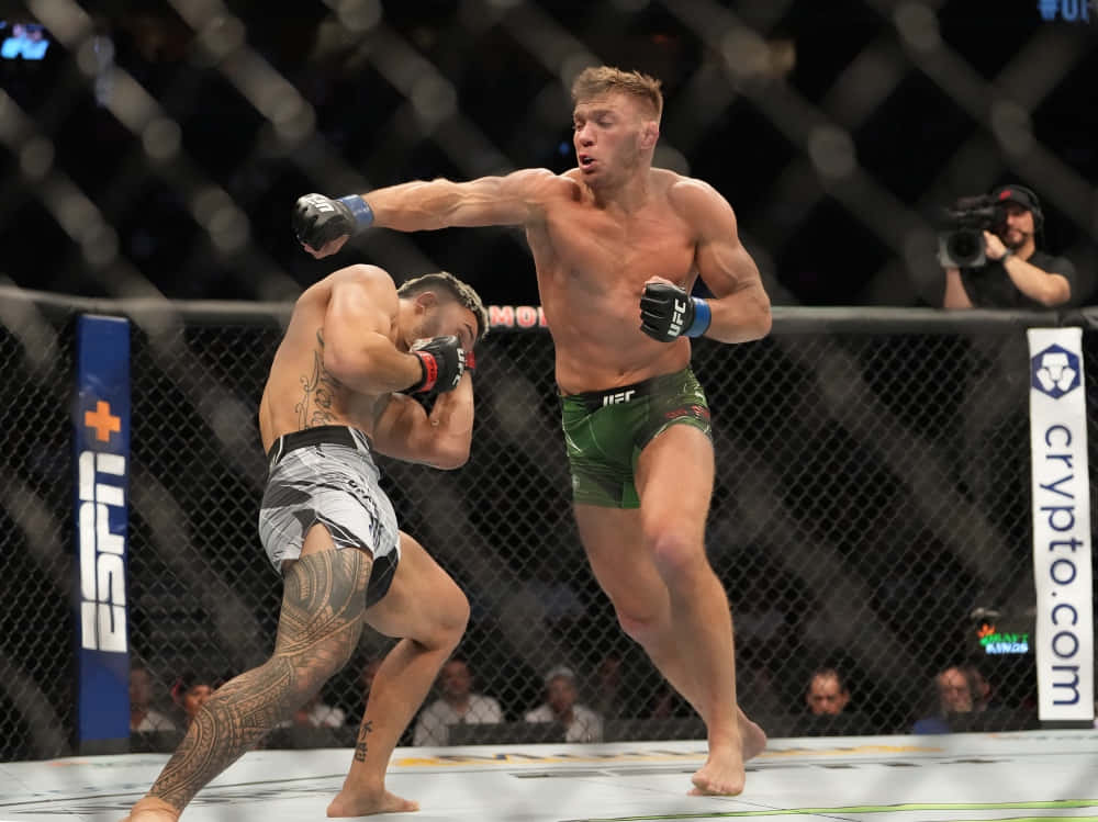 爆發瞬間：德里庫斯·杜普雷西斯揮拳 壁紙 — 兩名肌肉發達的拳手在UFC八角籠中交鋒，一人出拳，另一人在明亮的場館燈光下格擋。