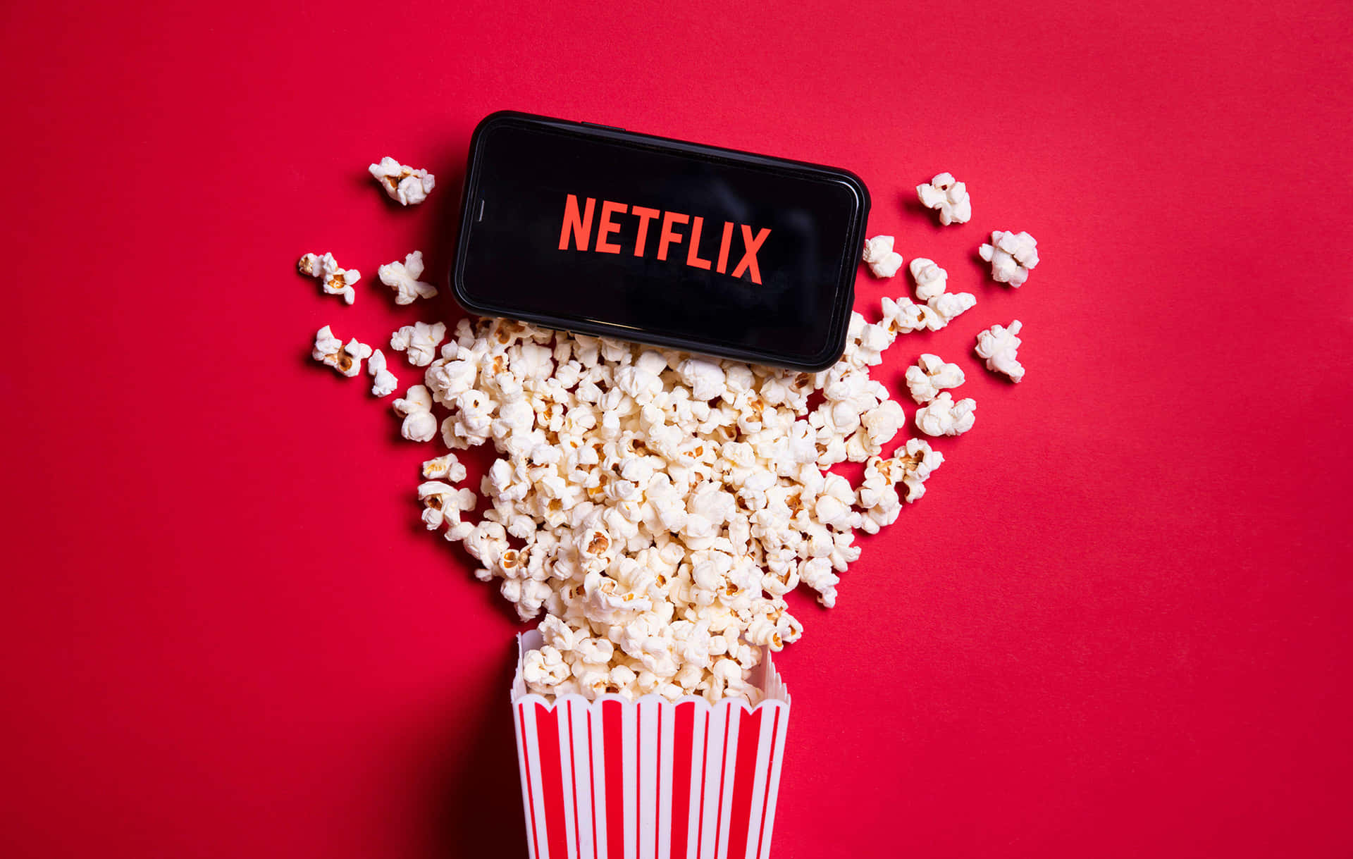 Netflix手機被條紋桶中的爆谷包圍，紅色背景