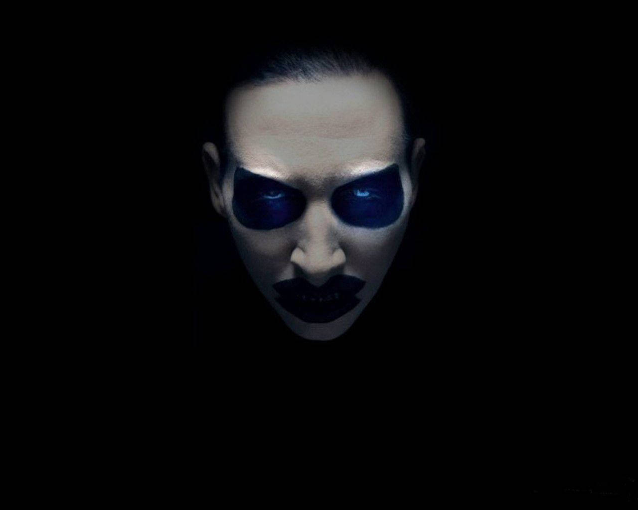 一個在黑色背景上帶有發光藍眼睛和深色化妝的人。