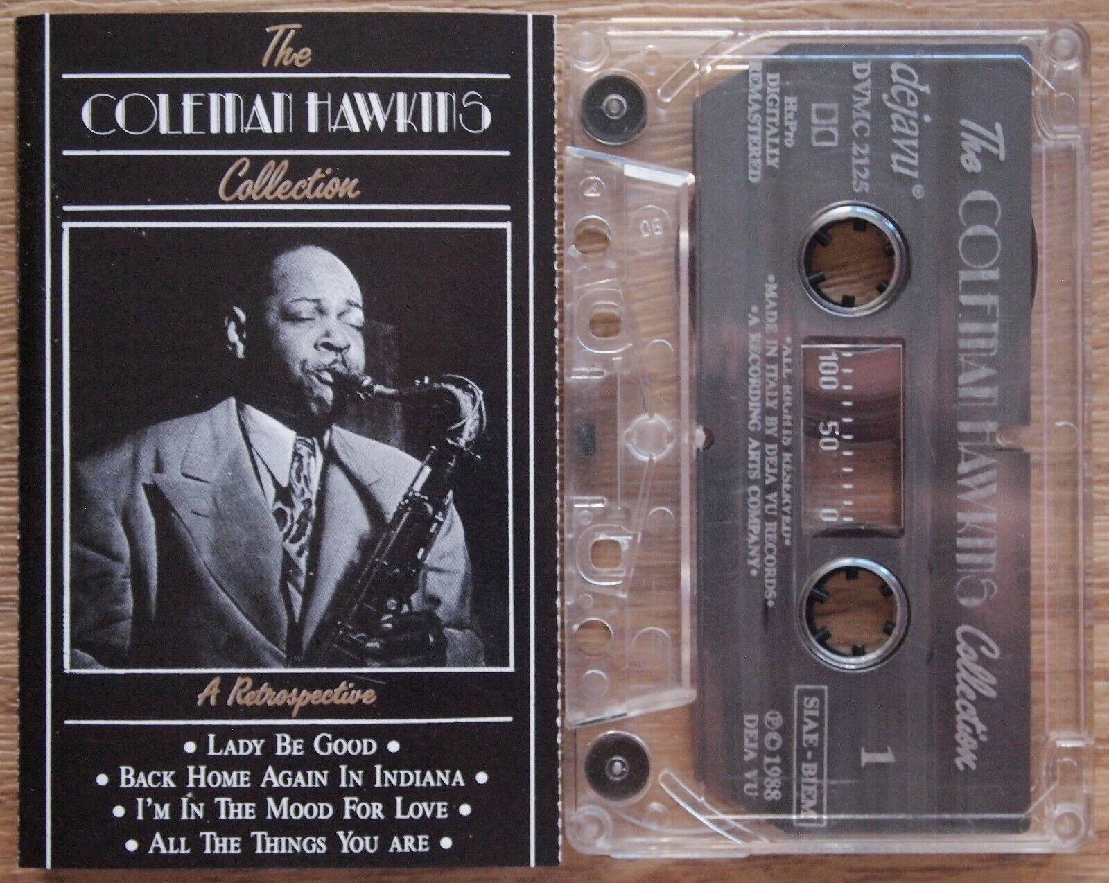 爵士傳奇Coleman Hawkins 演奏薩克斯風 壁紙 — 一個復古黑白卡式錄音帶和The Coleman Hawkins Collection的專輯封面，放在木質表面上。