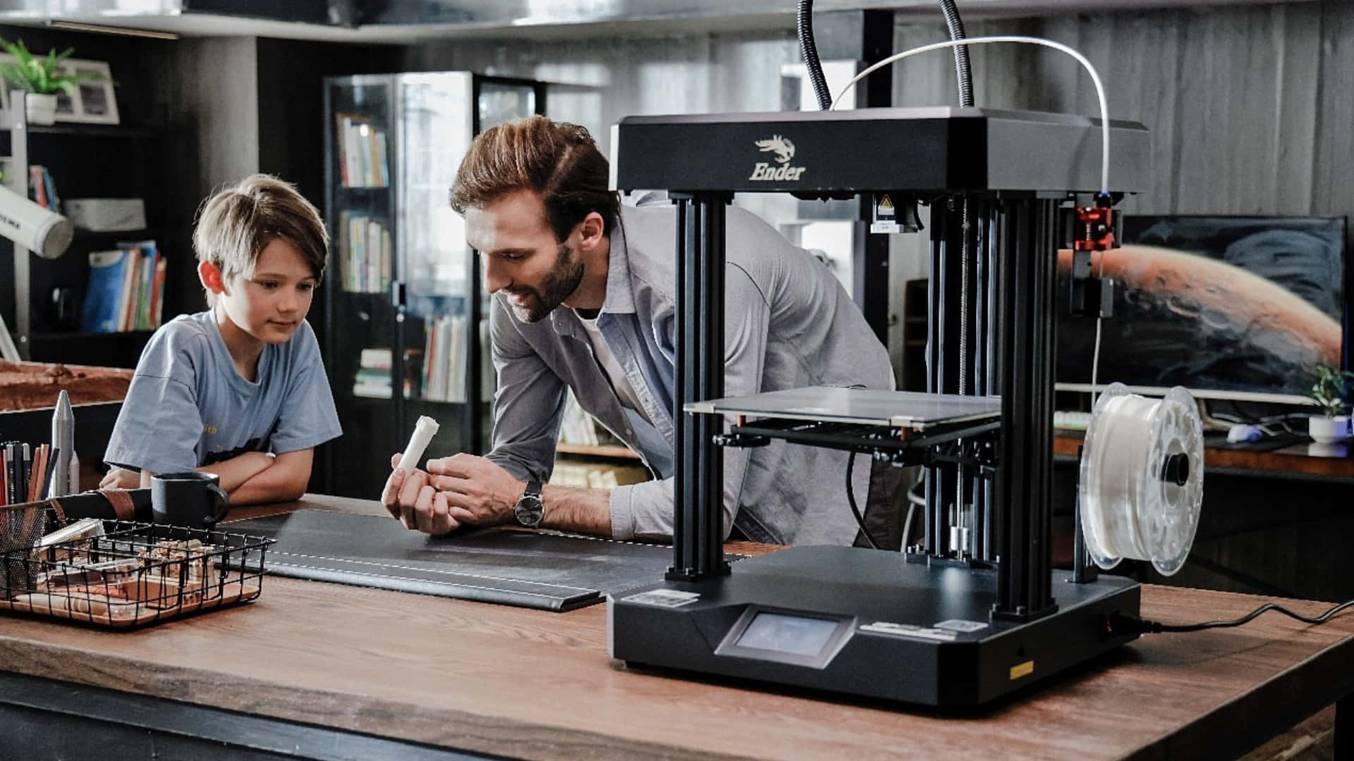3d Printer 桌布 壁紙 — 父親和兒子在一個充滿科技和書籍的現代家庭工作室中協作使用3D打印機。