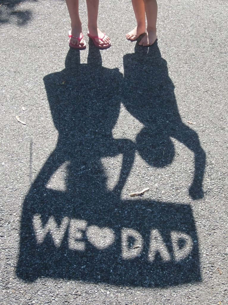 小孩的影子在行人路上用粉筆拼出「WE ❤️ DAD」。
