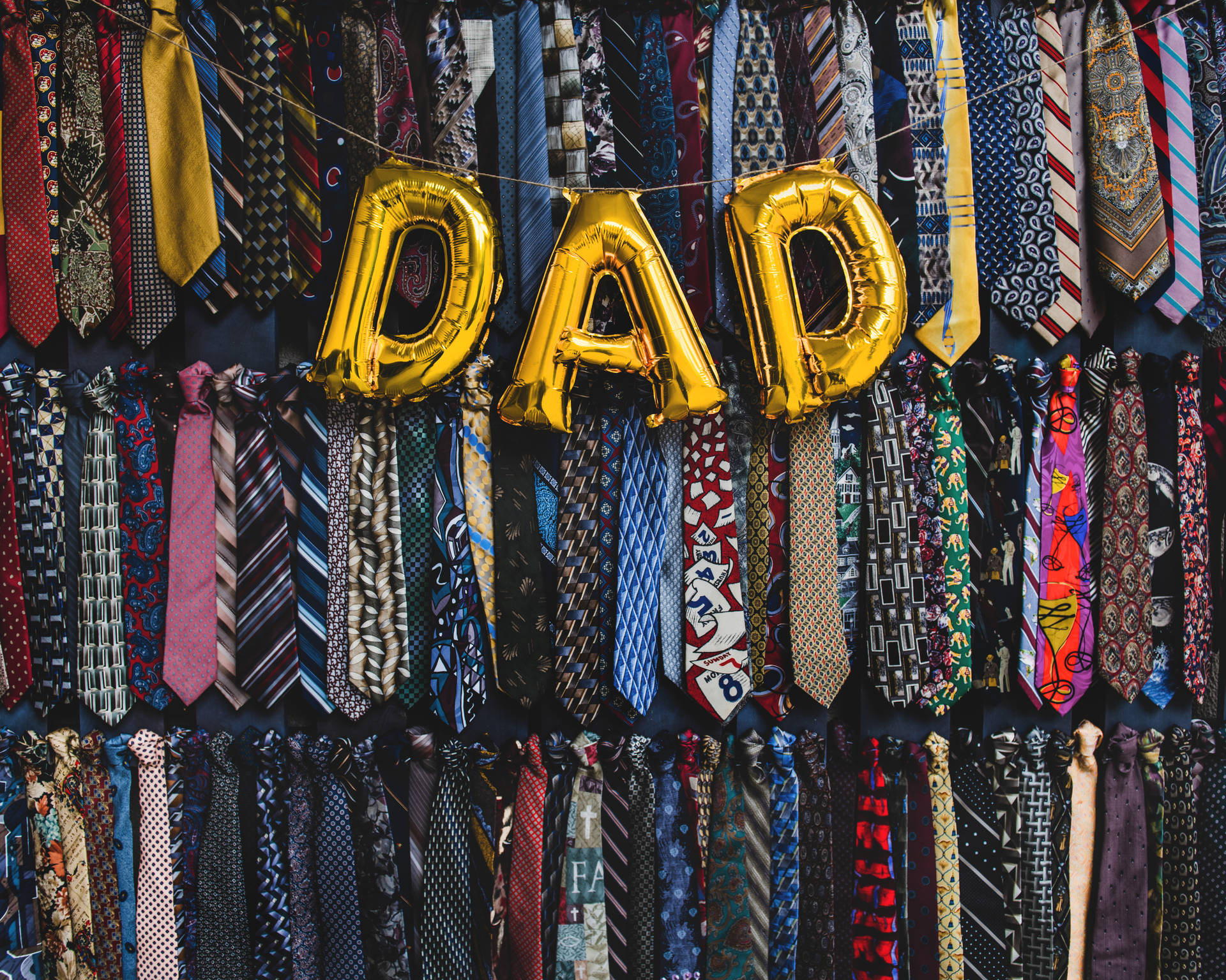 金色 DAD 氣球懸掛在各種領帶牆之間，慶祝父親節。