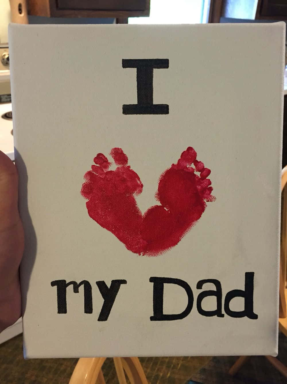 手工製作的帆布藝術品，嬰兒腳印形成心形，並有文字「I love my Dad」。